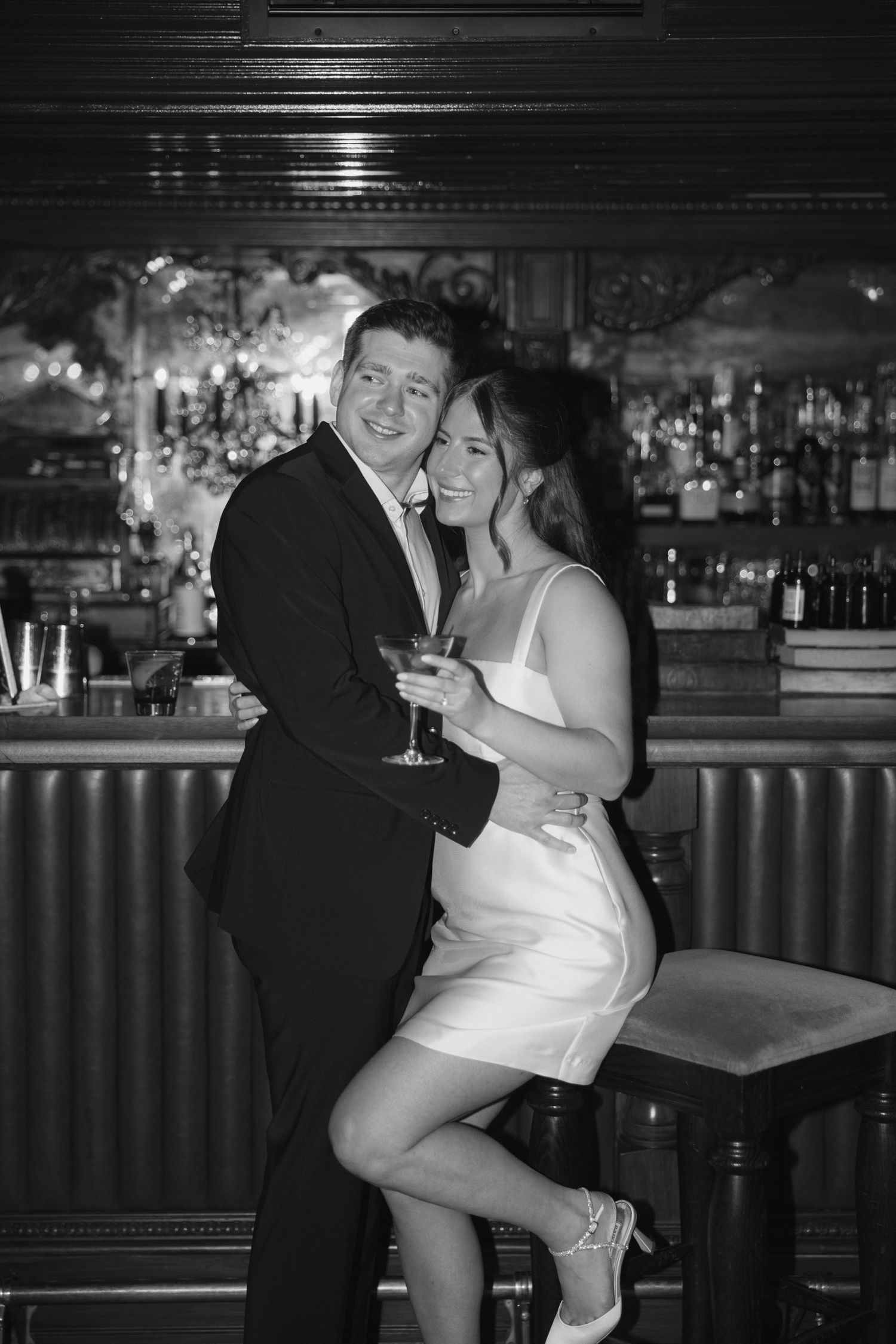 A couple in formal attire shares a romantic dance together at a dimly lit bar.