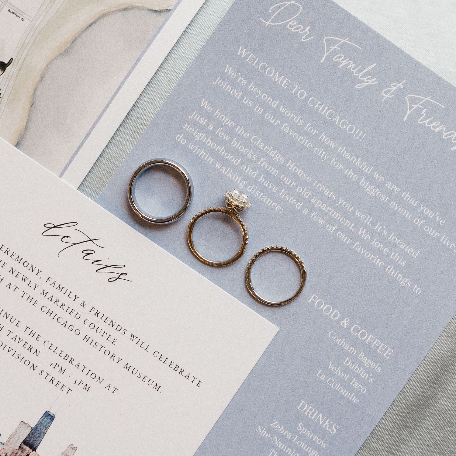 Wedding invitation suite with elegant calligraphy and wedding rings arranged on a light neutral background.