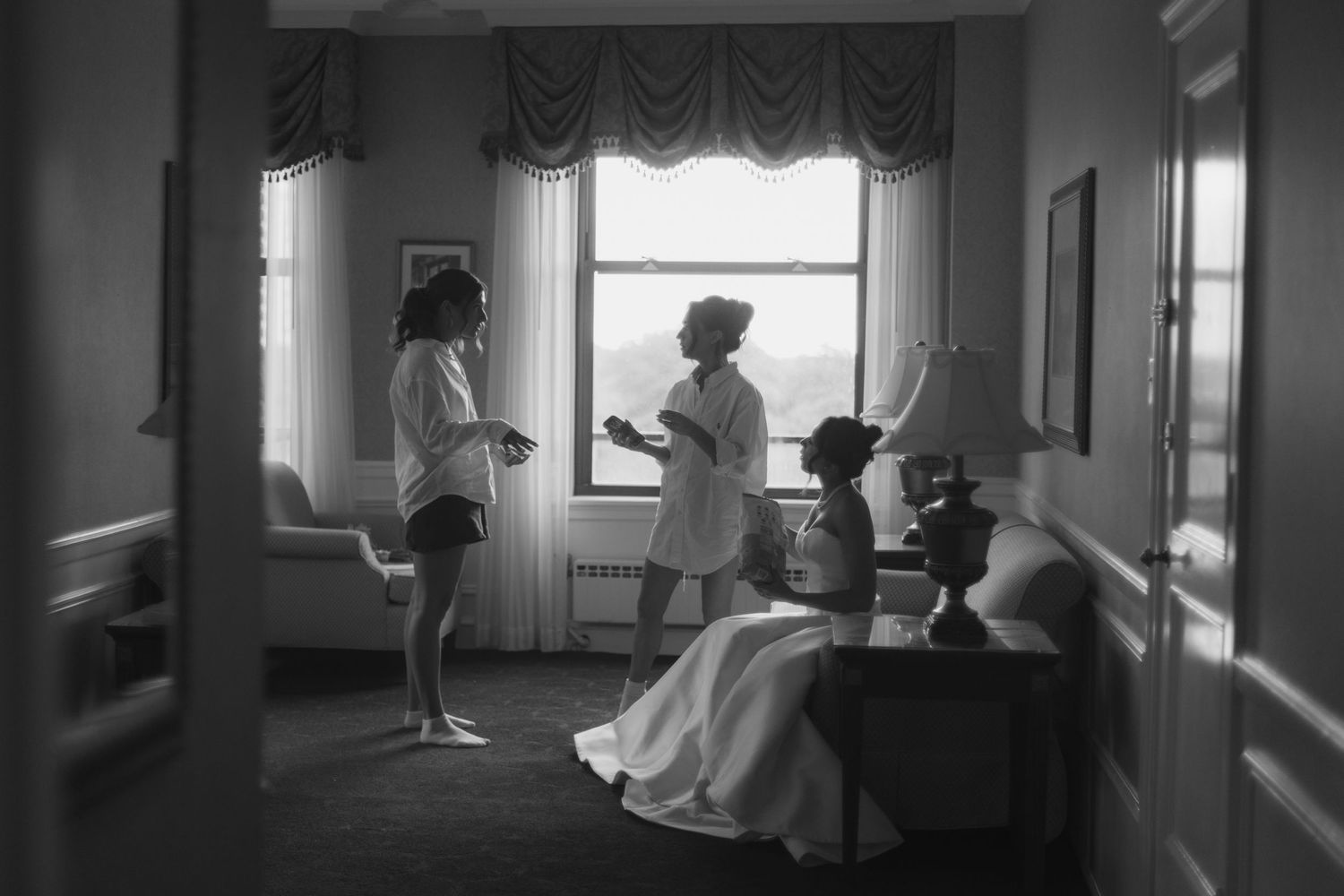 Black and white photo of two women in robes preparing in an elegant hotel room before a wedding ceremony.