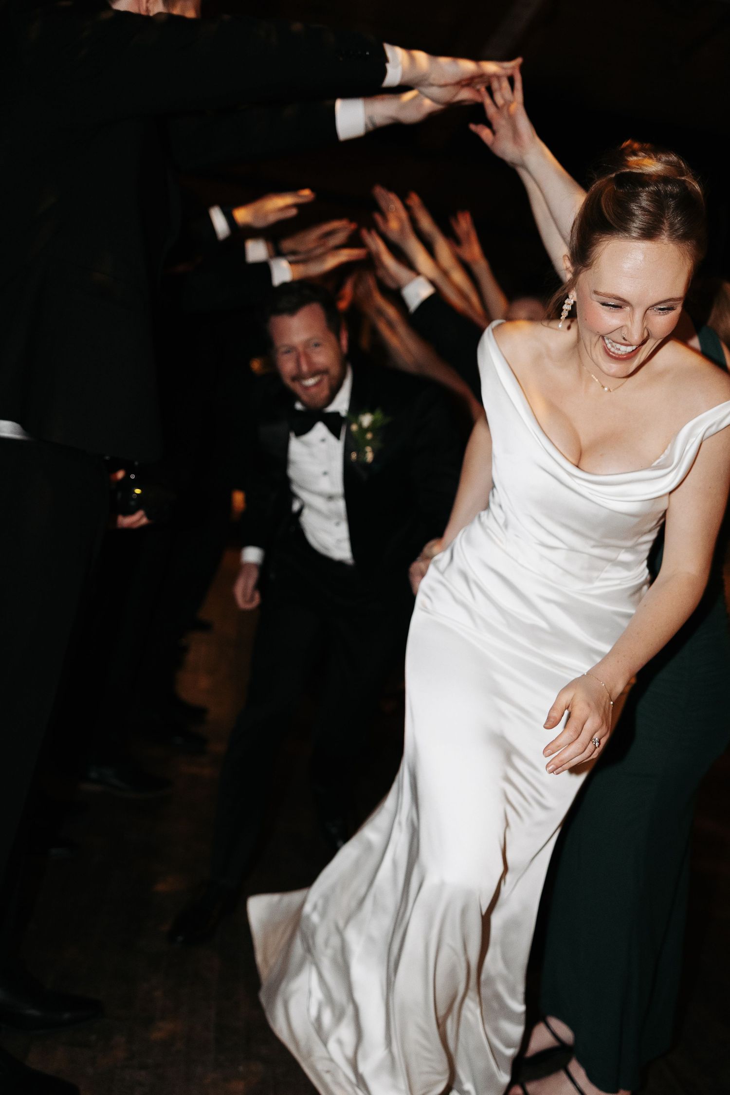 A joyful celebration at a wedding reception shows dancing and laughter in an energetic candid moment.