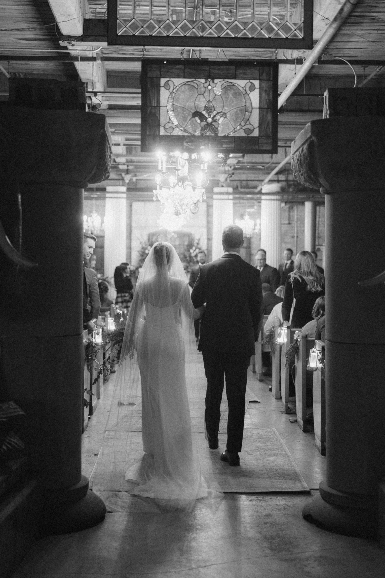 Black and white wedding photo sequence showing a bride and groom walking down a dimly lit industrial hallway.