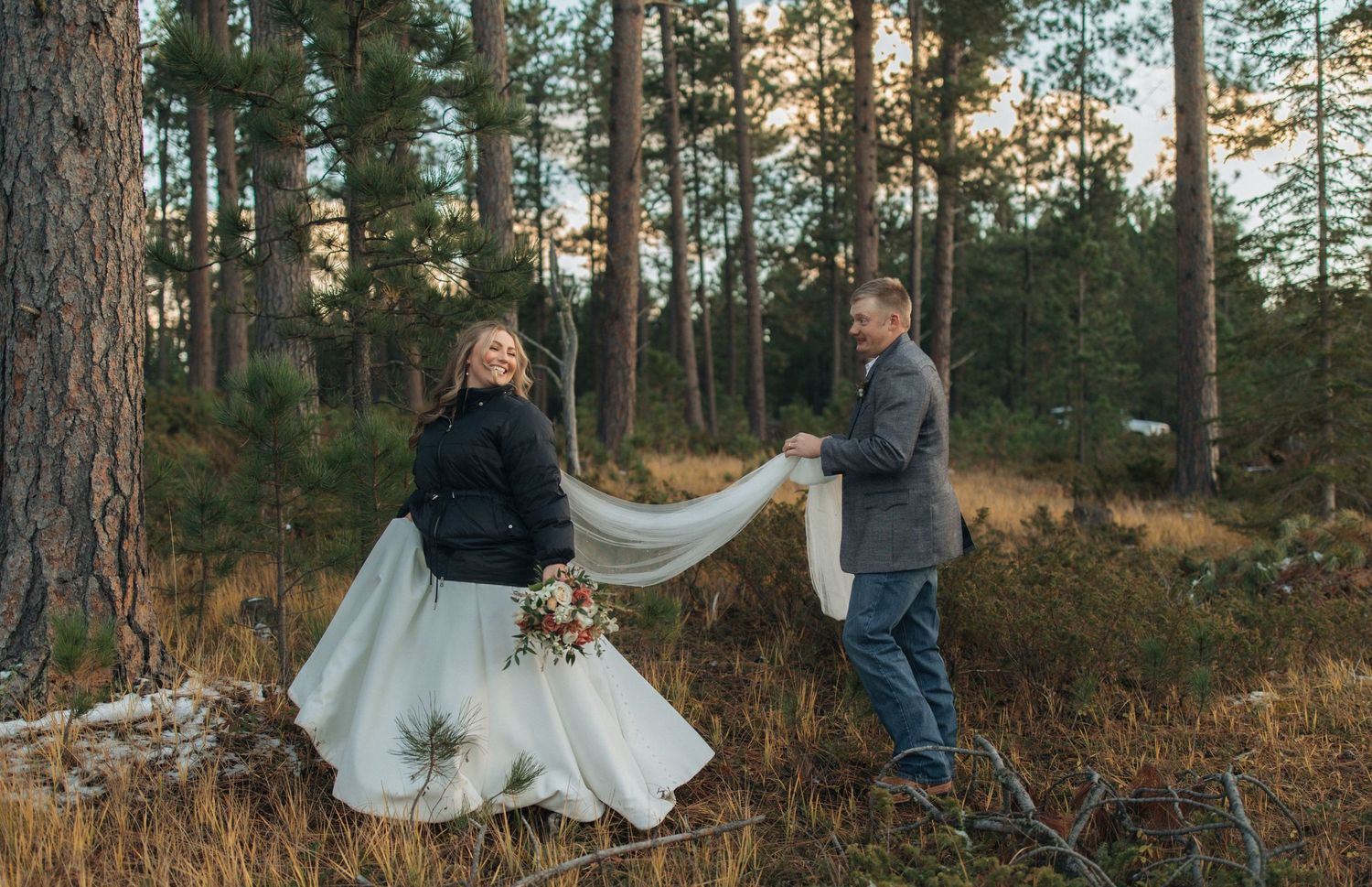 A couple dancing in a forest setting at sunset with the bride wearing a flowing white dress.