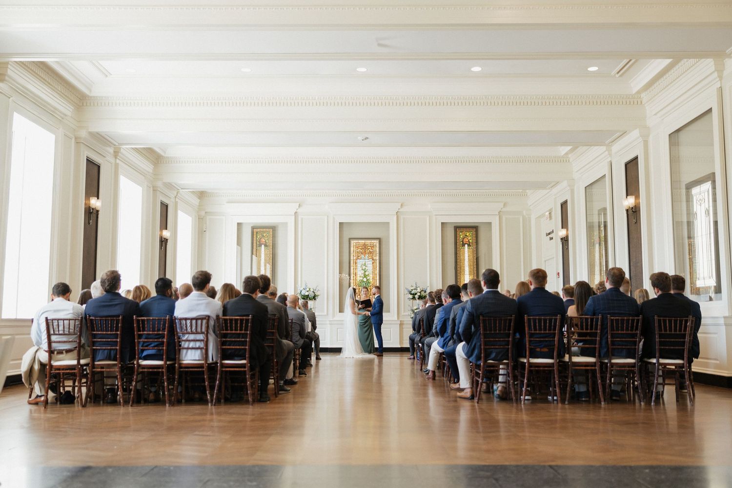 A long white corridor with tables and chairs arranged in rows along the walls for dining or meetings.