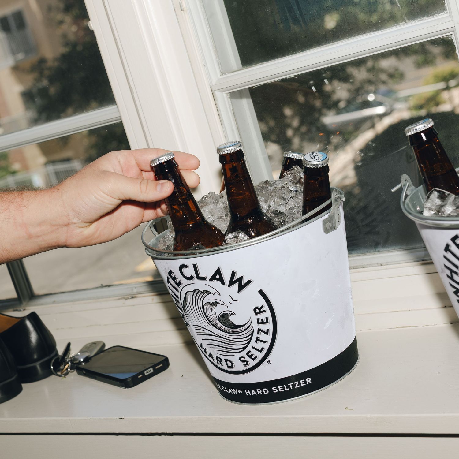 White Claw hard seltzer cans arranged in a row on a windowsill with natural lighting.