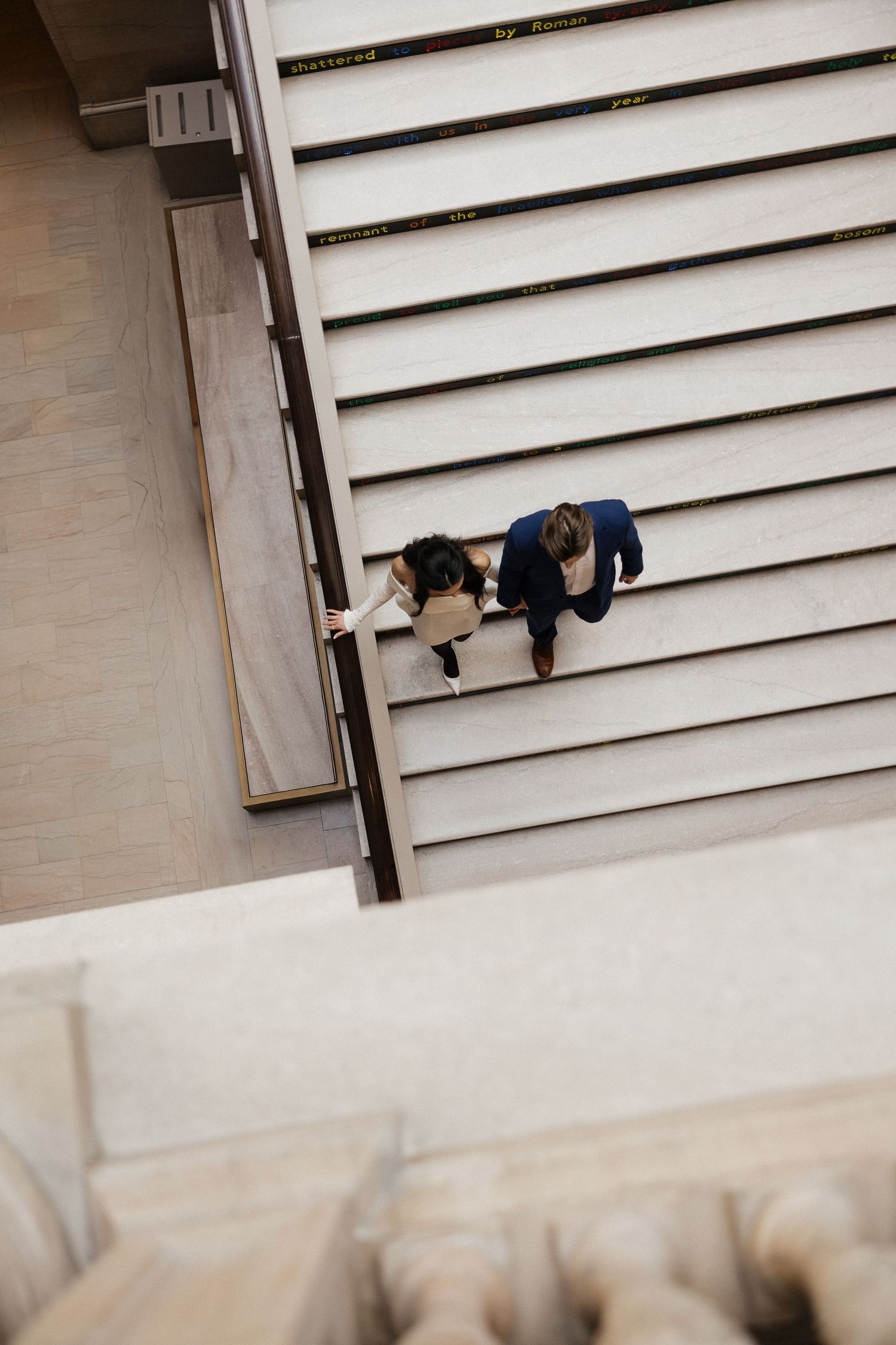 A couple embraces on white stairs in an artistic composition.