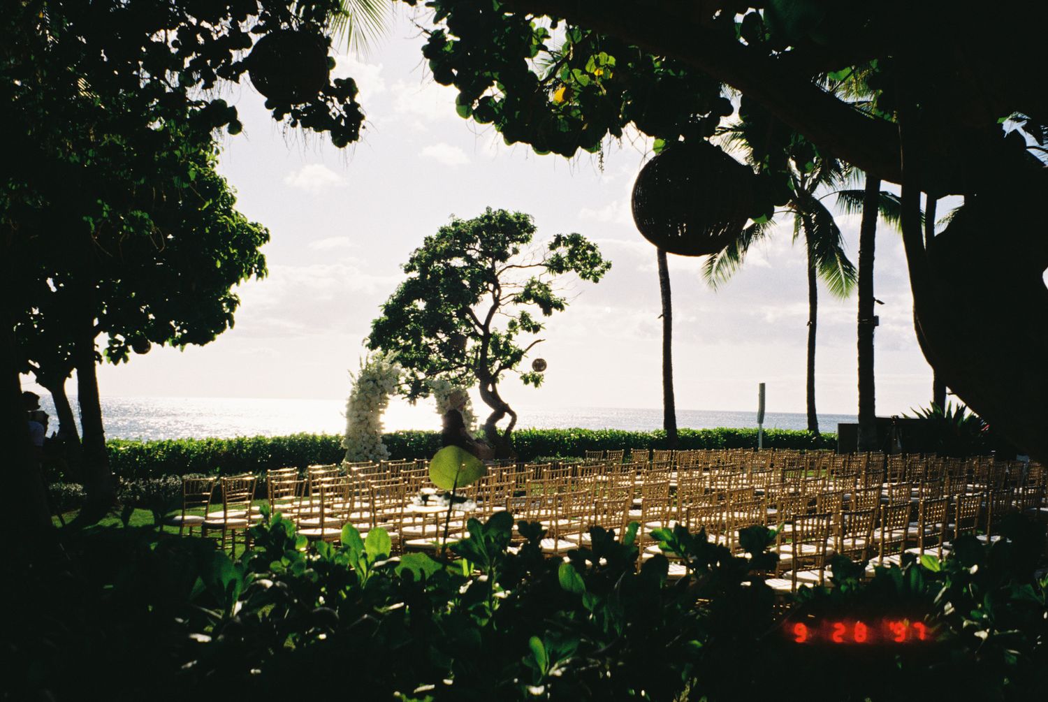 Silhouetted trees and wooden fence line a rural hilltop against a dramatic cloudy sky at sunset.