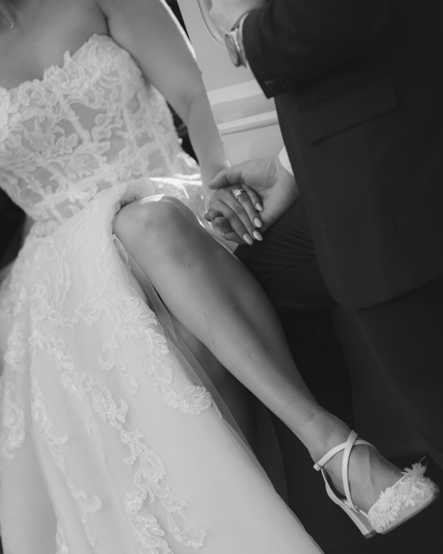 Close-up details of a white lace wedding dress with delicate embellishments.