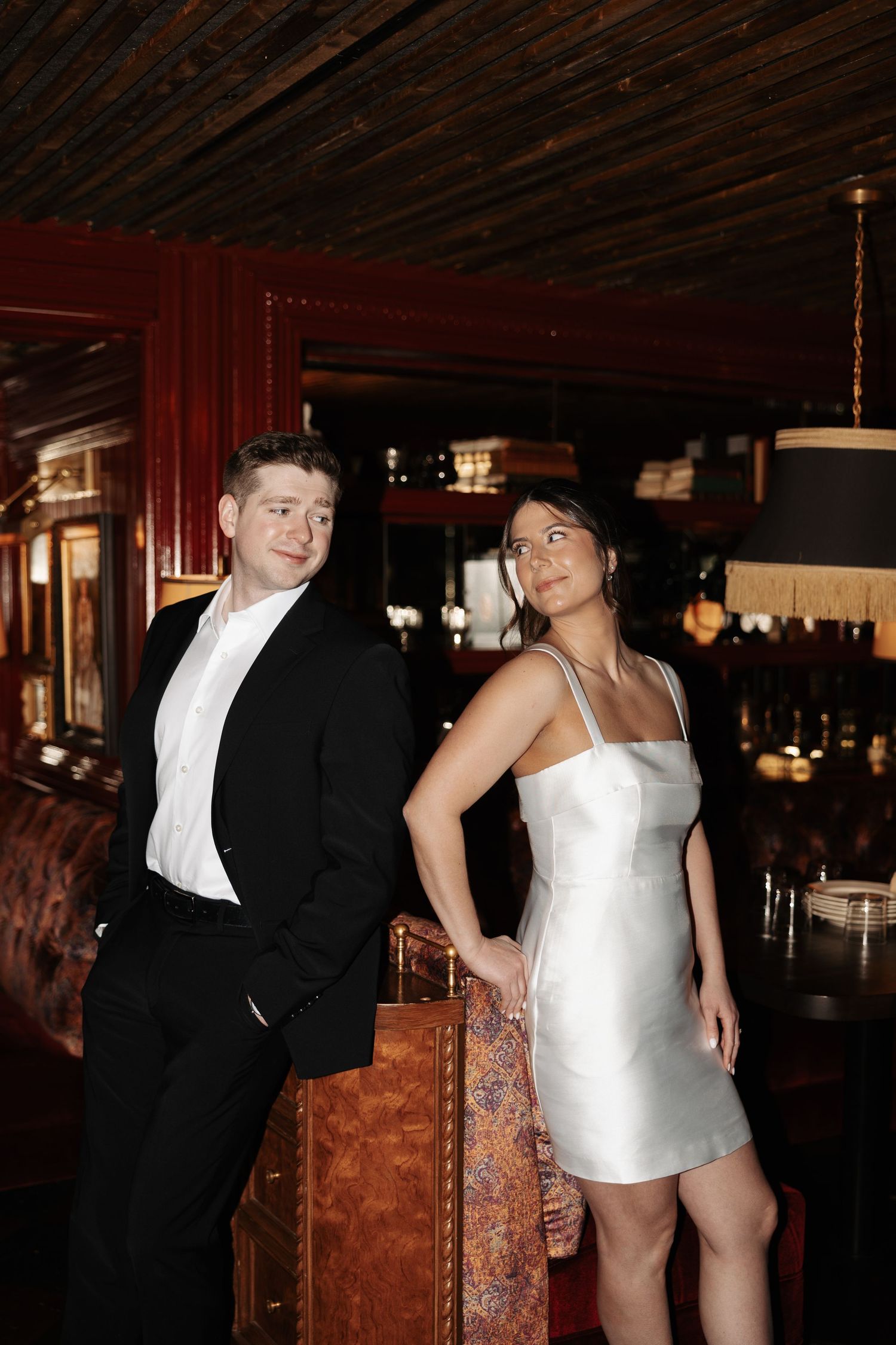 A couple in formal attire dances together at an evening event in a dimly lit venue.