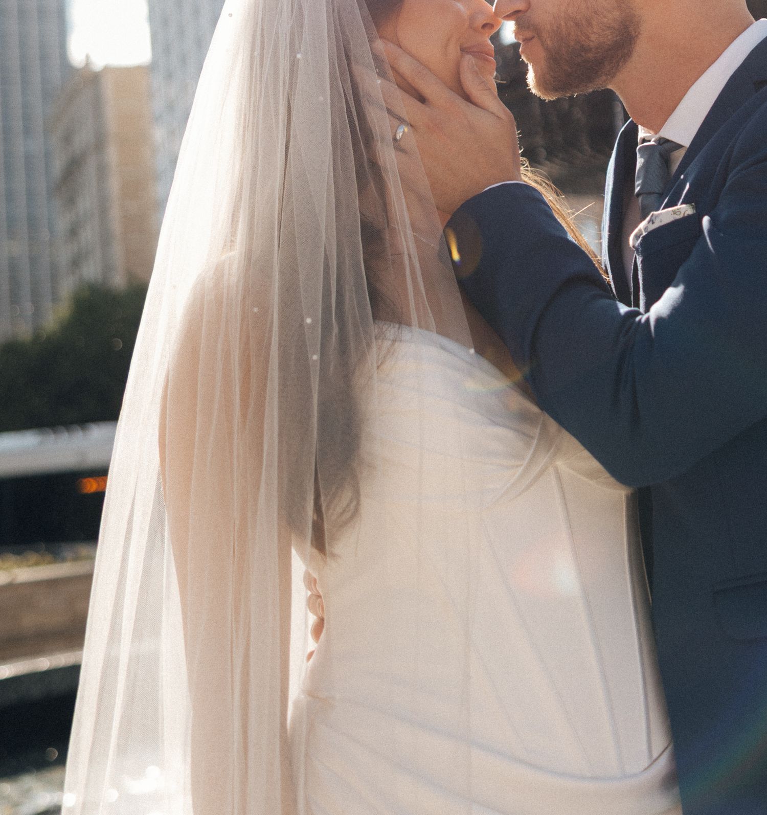 A bride and groom share an intimate moment during their wedding ceremony with a soft veil and elegant attire.