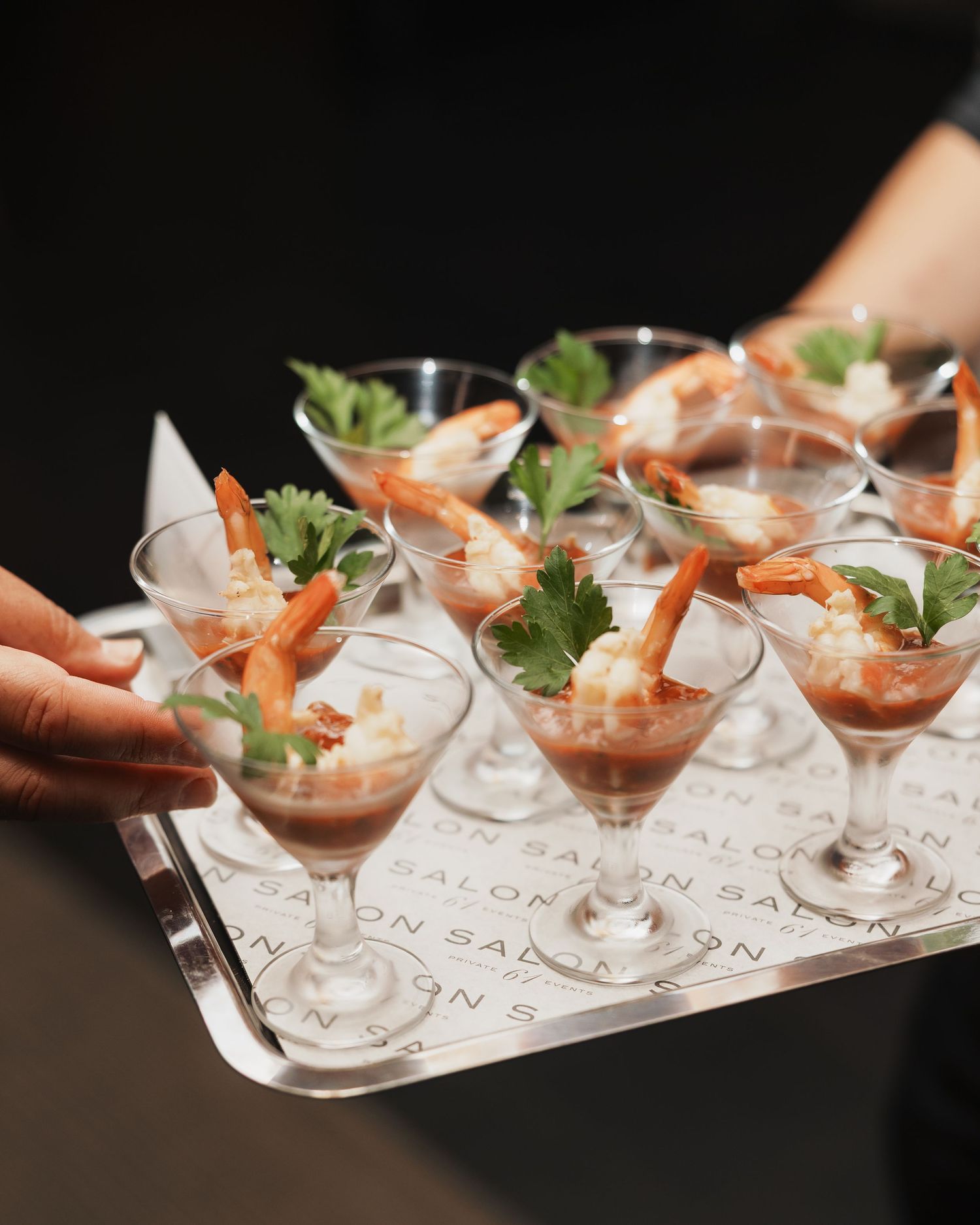 Elegant shrimp cocktail appetizers served in martini glasses on a silver tray at a Salon catering event.