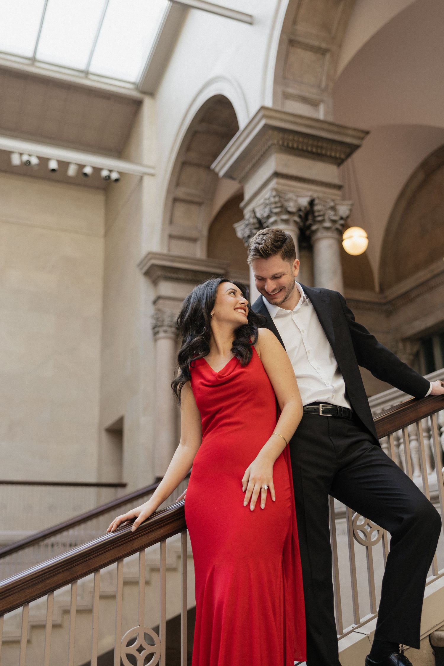 A couple shares an intimate dance moment in an elegant hallway with classical architecture and natural lighting.