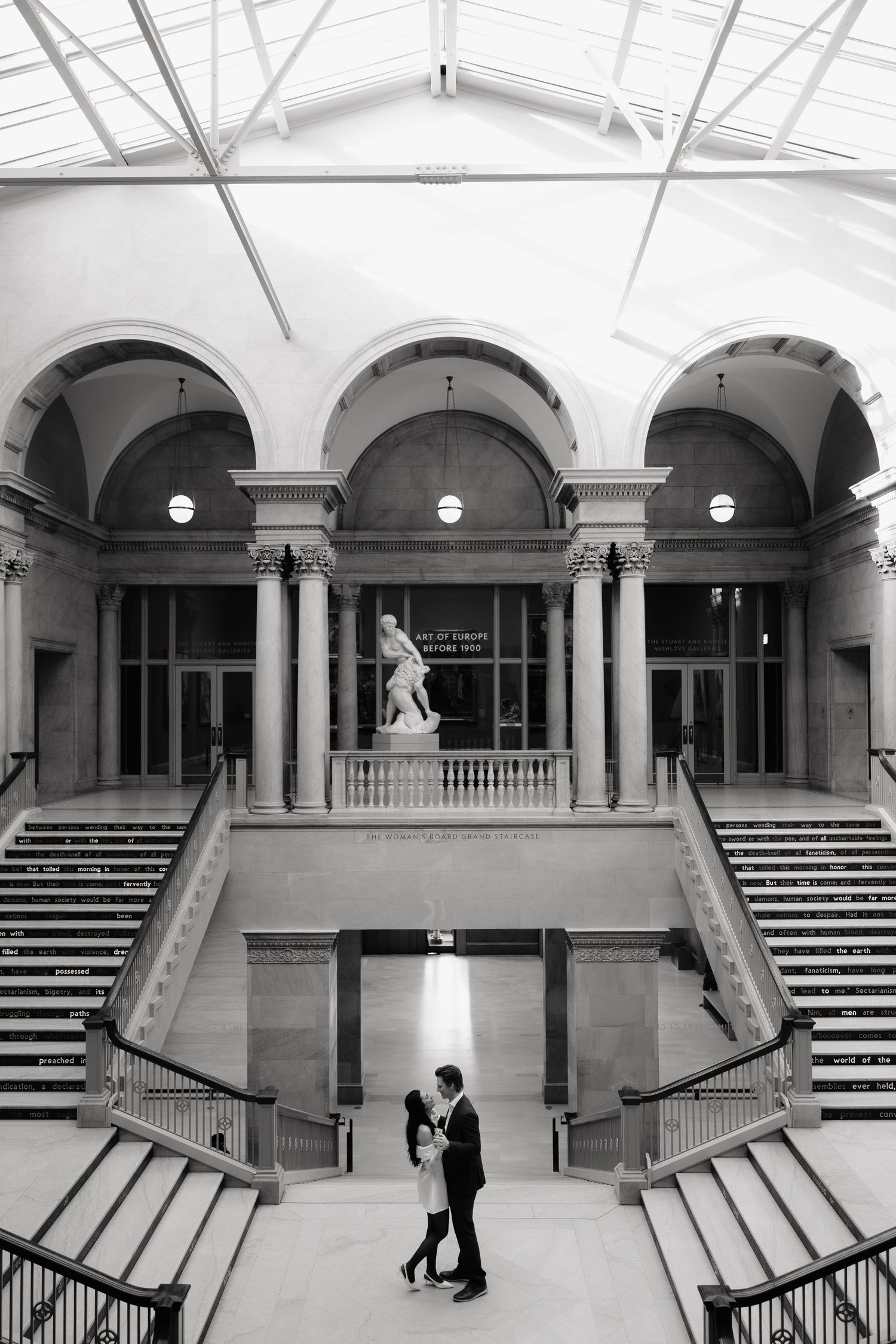 Wide angle view of an elegant marble interior with grand staircases and arched columns.