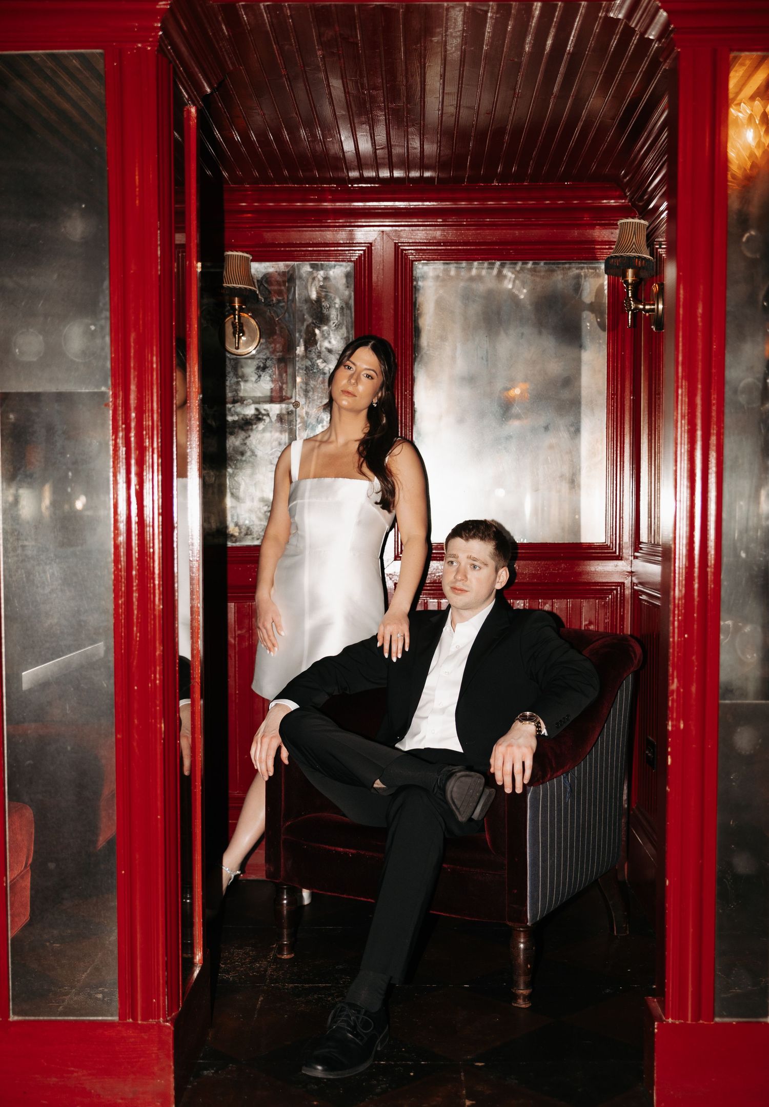 Artistic portrait series in a dimly lit hallway with red walls featuring formal evening wear.