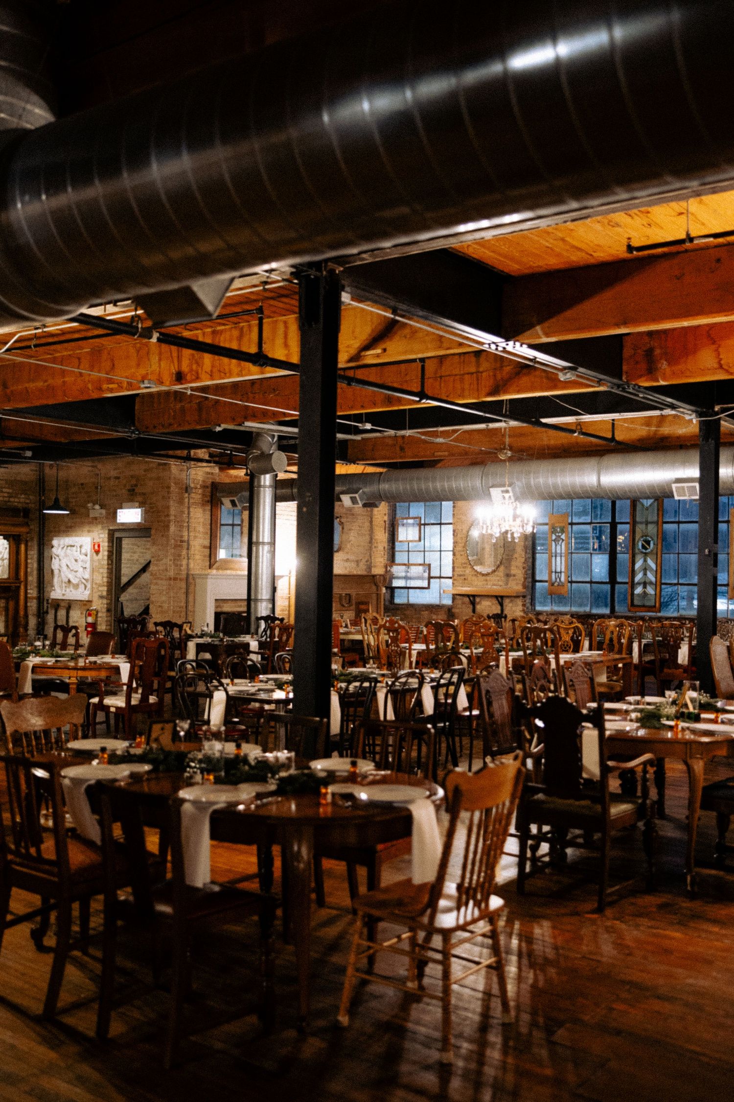 Rustic industrial restaurant interior with exposed brick walls, wooden tables, and vintage lighting in a converted warehouse space.