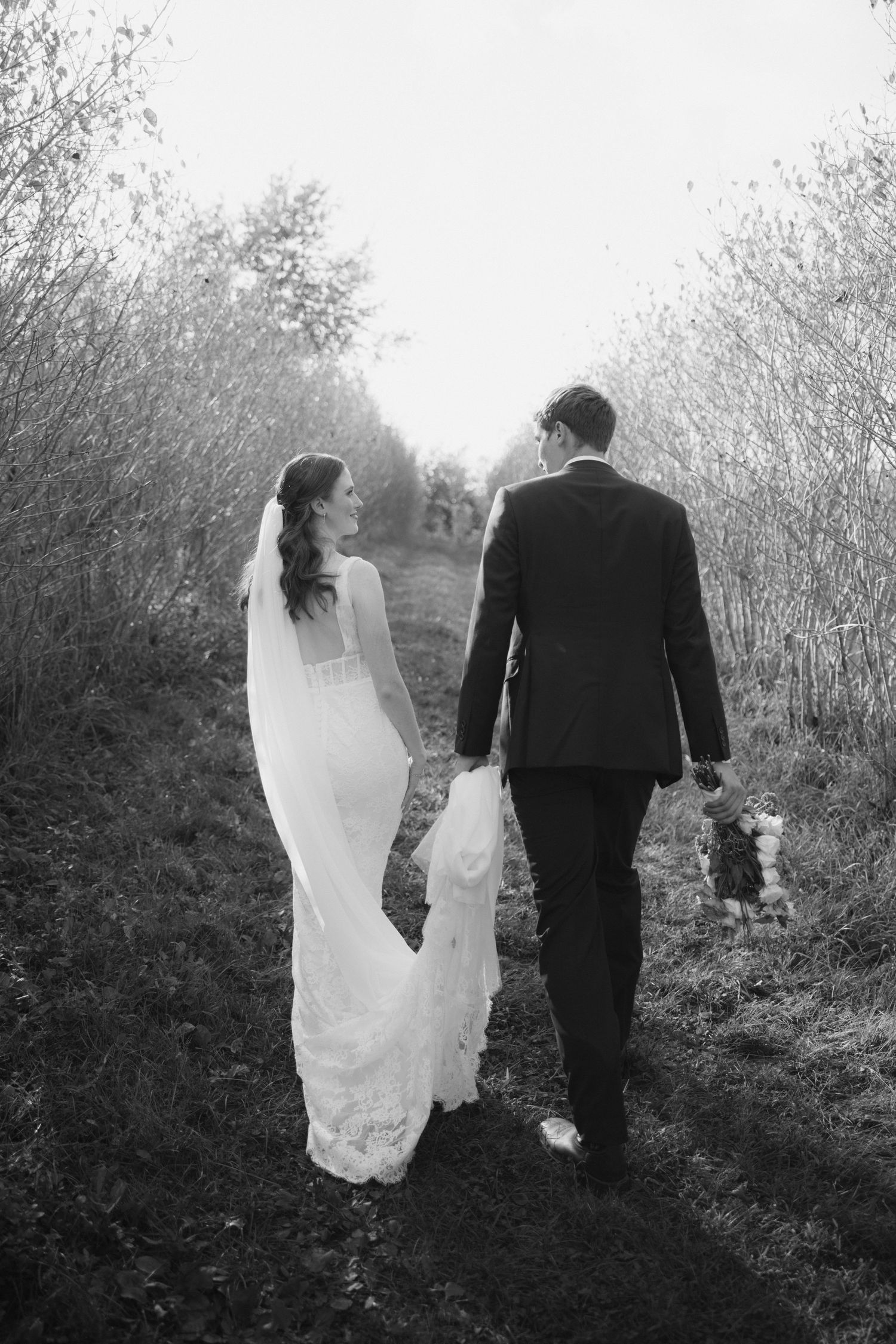 Black and white photo series of a bride and groom walking together through a misty outdoor path.