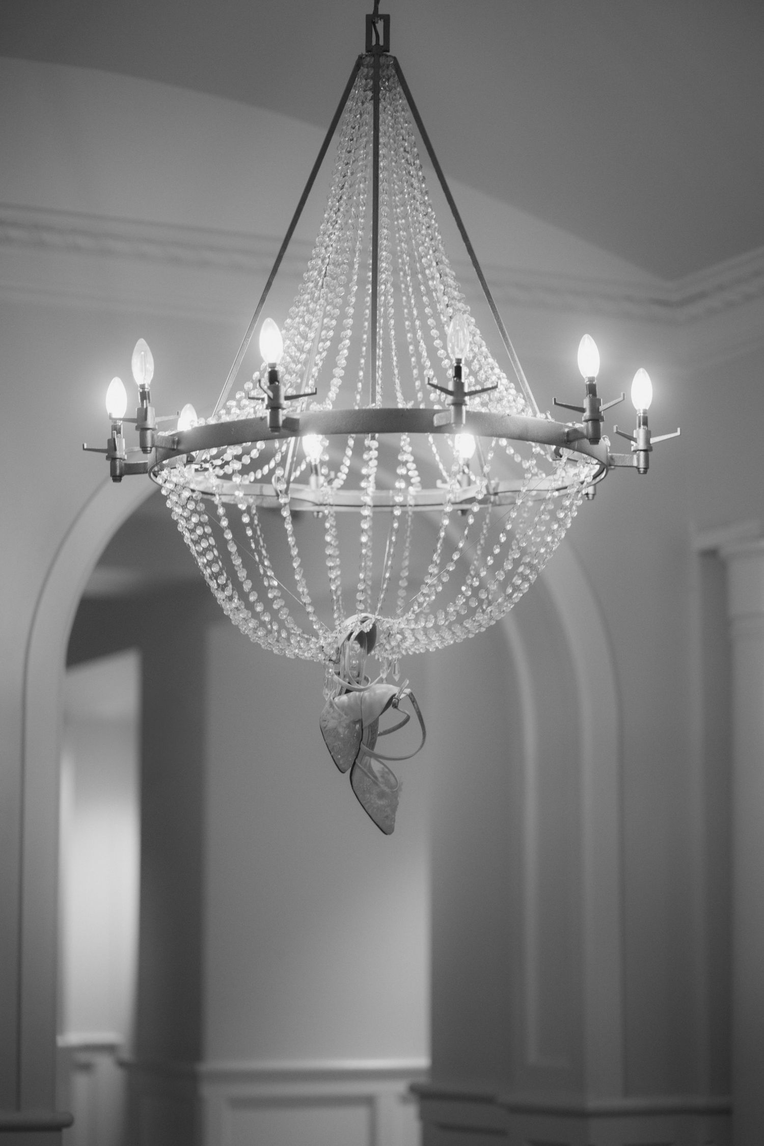 Crystal chandeliers with elegant beaded strands hang from the ceiling in a formal setting.