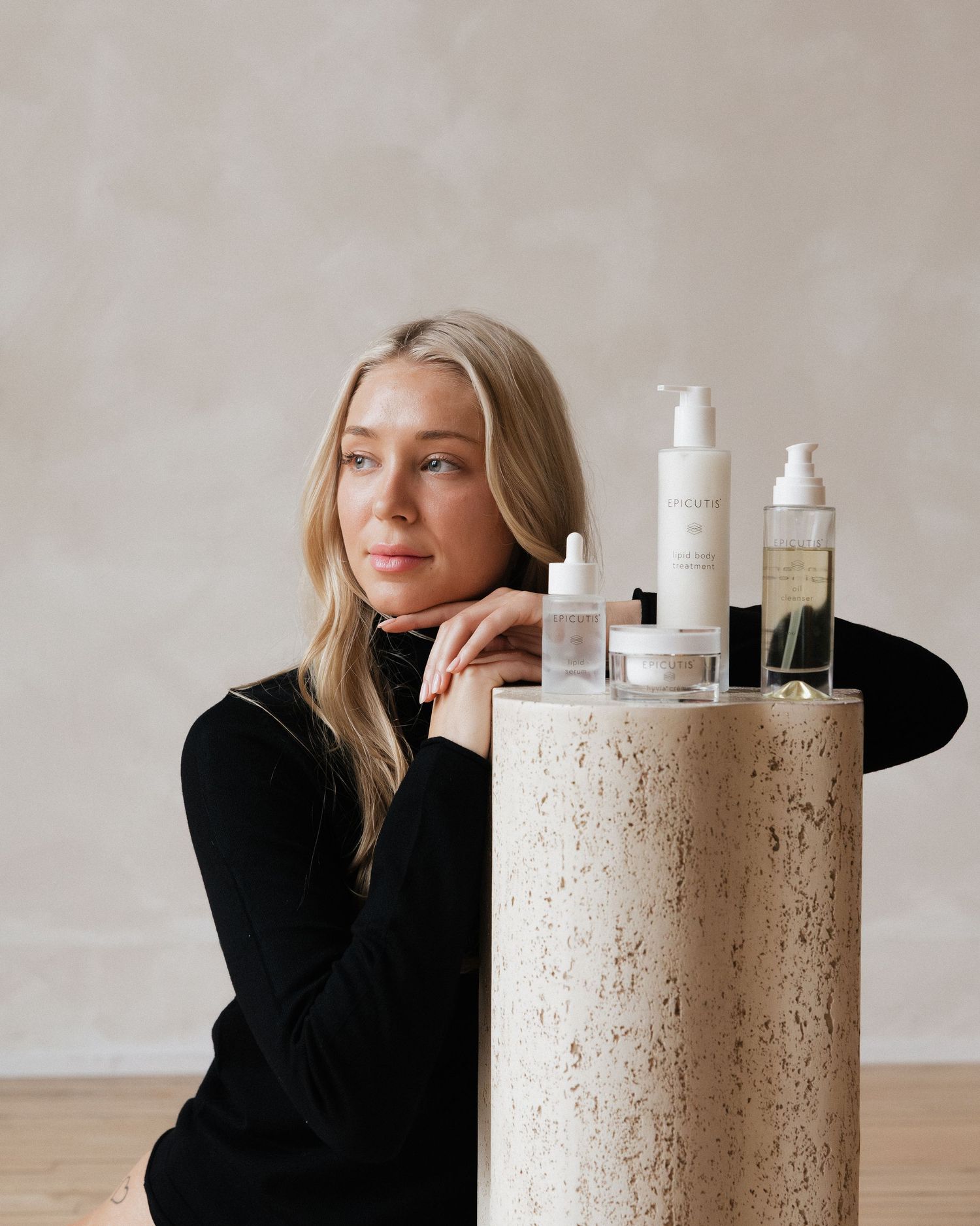 A series of skincare product bottles displayed on a textured concrete pedestal against a neutral background.