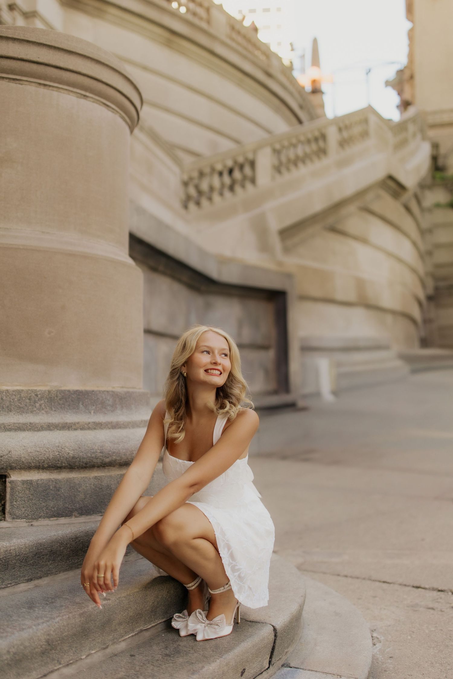 Elegant portrait session on stone steps with architectural details in warm lighting.