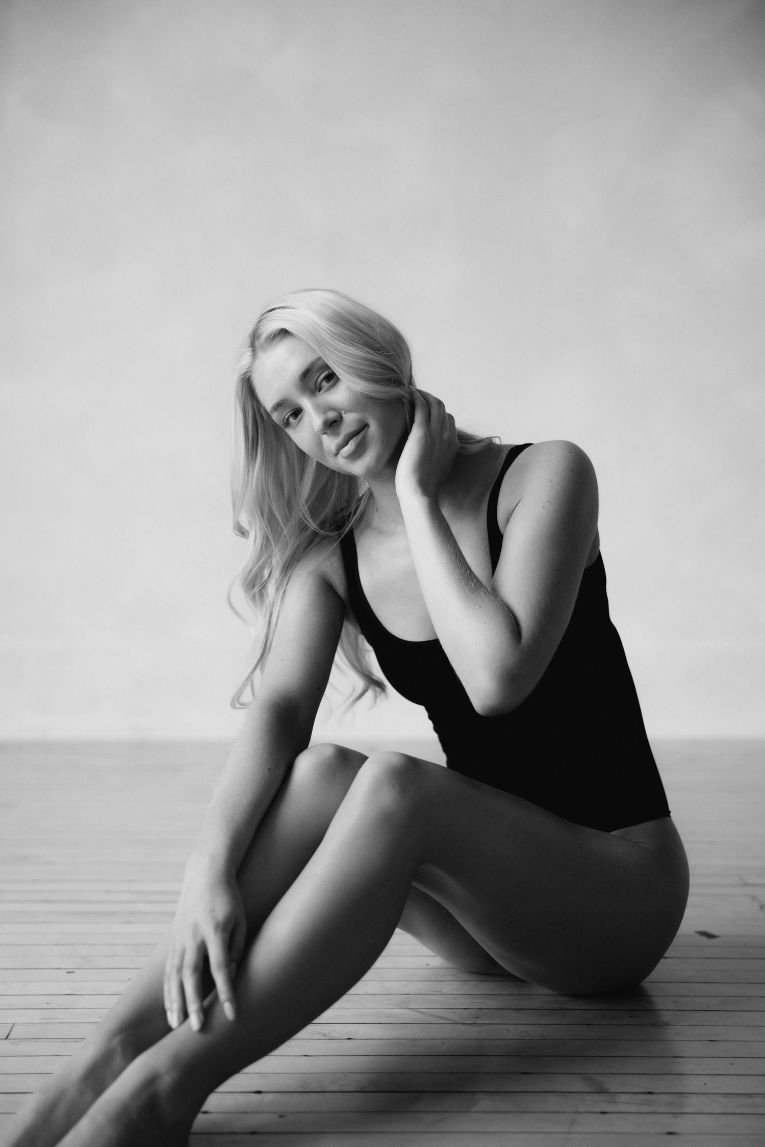 Black and white artistic photo series showing a figure in dark clothing reclining on wooden floor in various poses.