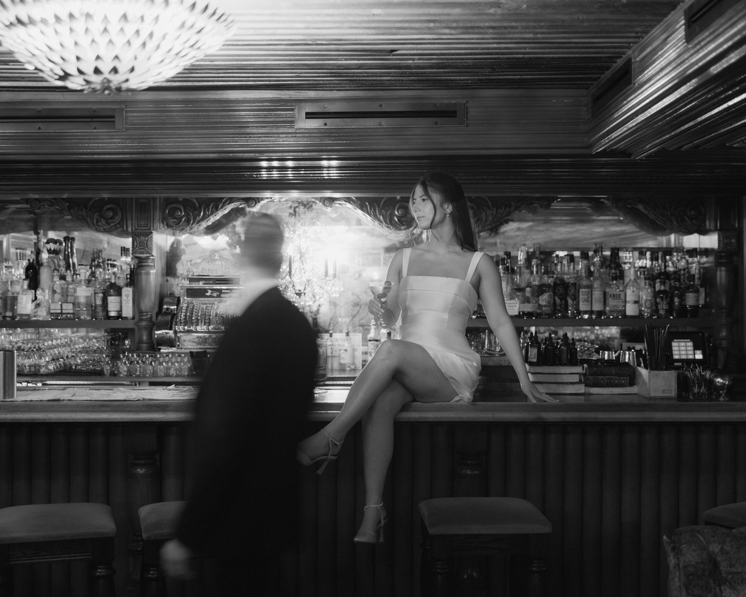 A series of black and white photographs showing a dimly lit bar interior with patrons seated at counter.
