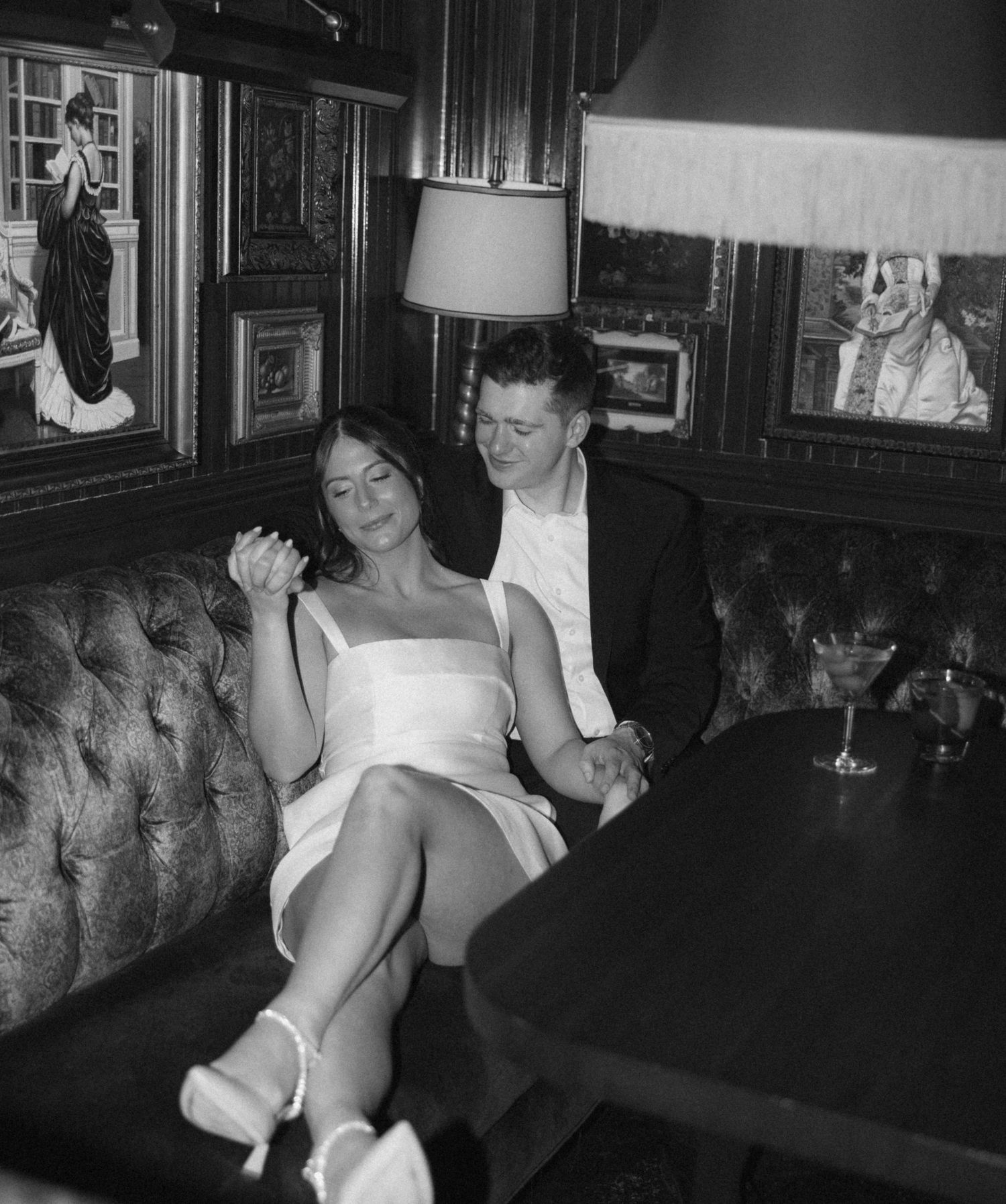 A black and white photograph shows people sitting in a dimly lit lounge or bar area.