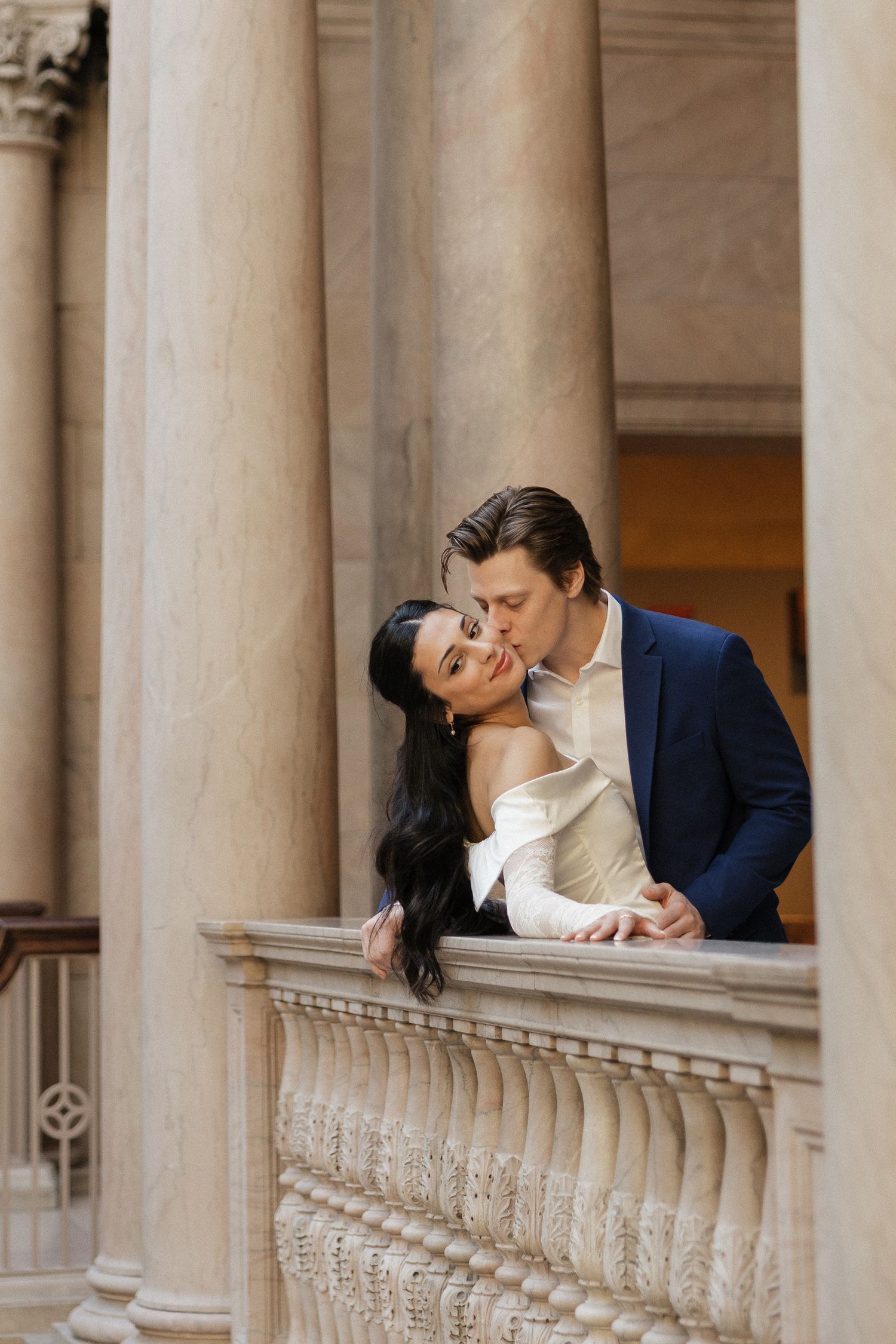 Romantic moment between couple among classical stone columns in elegant architecture.