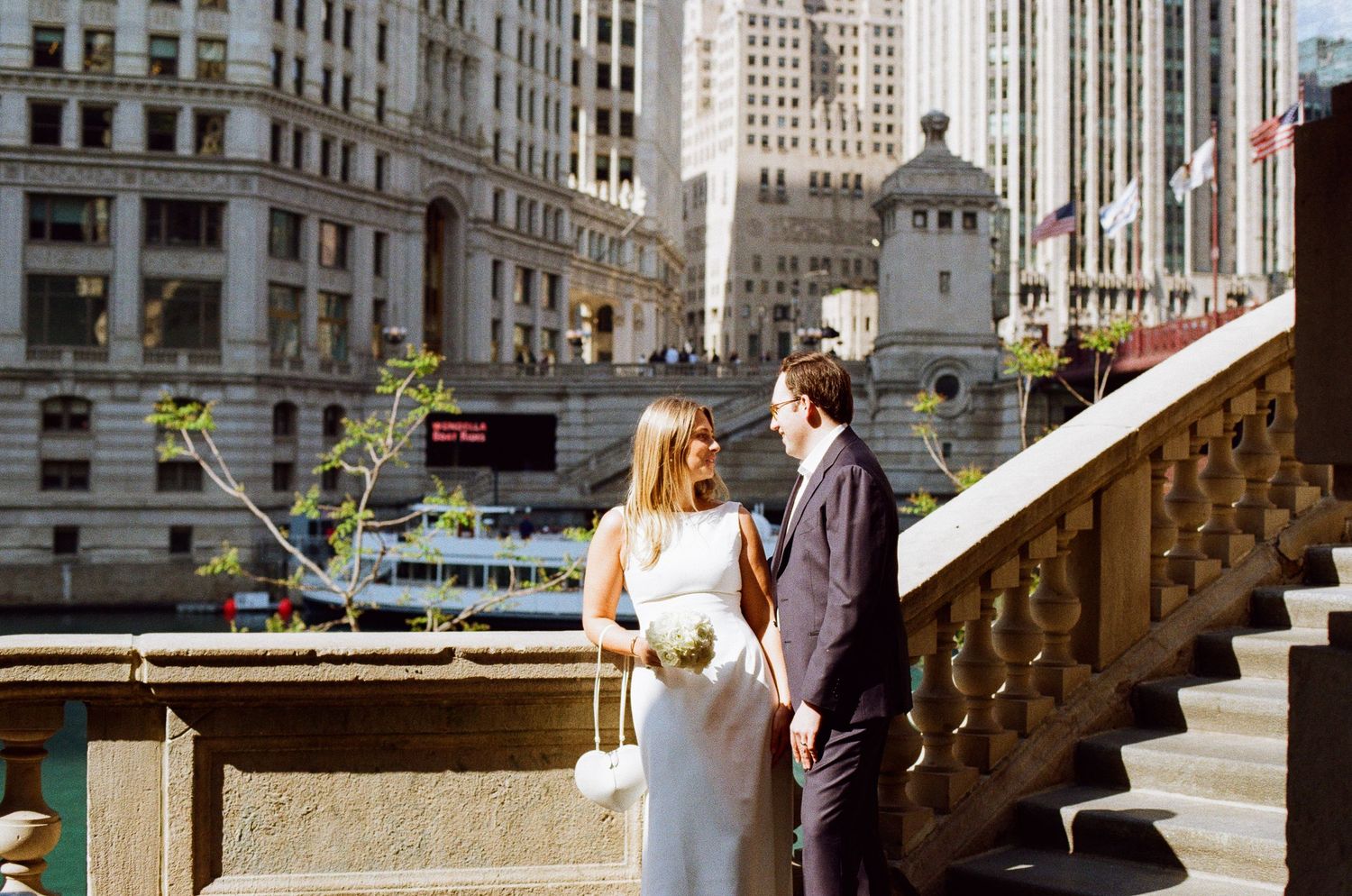 Bride and groom share a romantic moment on Chicago Riverwalk stairs with city skyline backdrop on their wedding day.