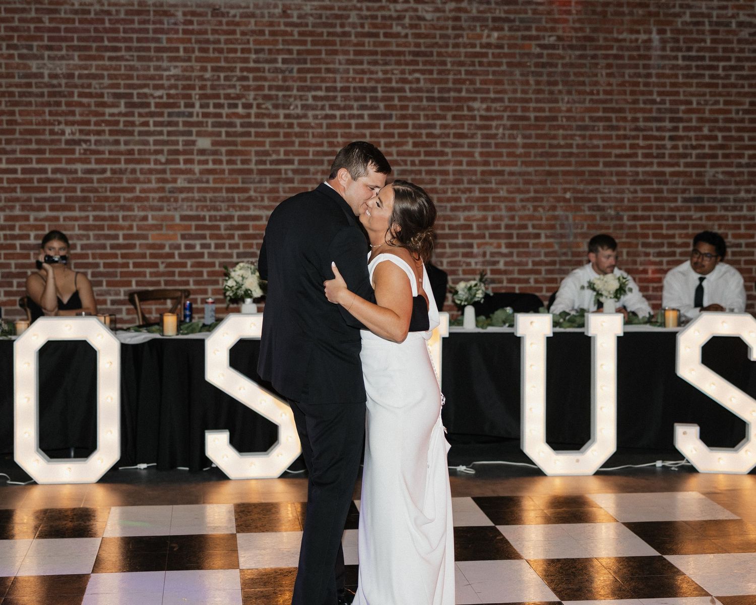 Wedding reception dance floor with guests celebrating under ambient lighting.