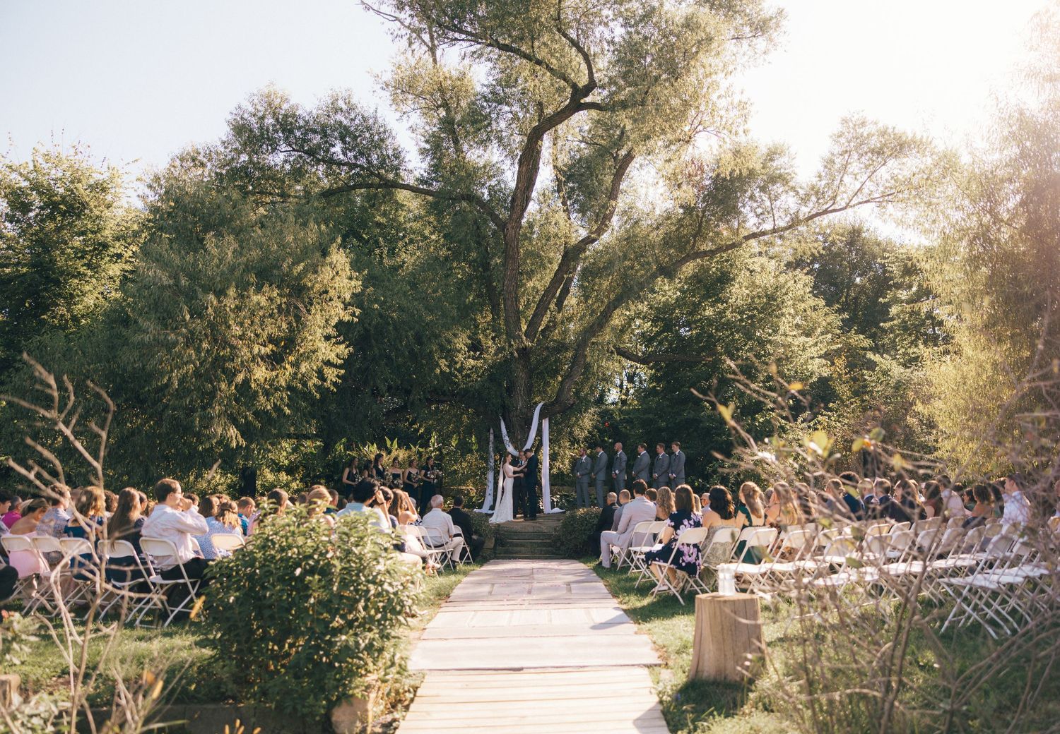 Outdoor wedding ceremony setup with rows of chairs and natural landscaping.