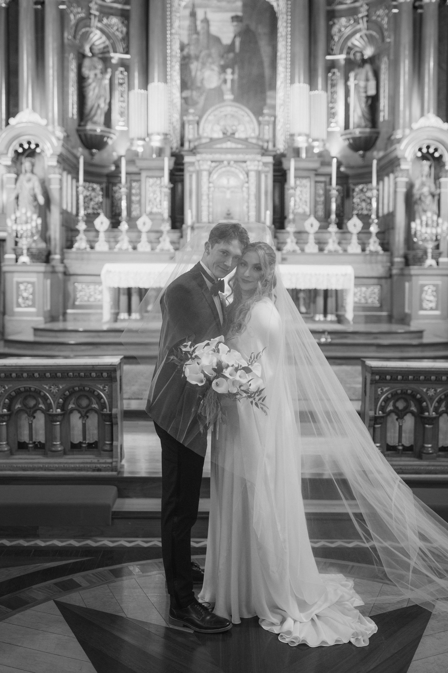 Wedding ceremony in an ornate church with elegant chandeliers and decorative altar.