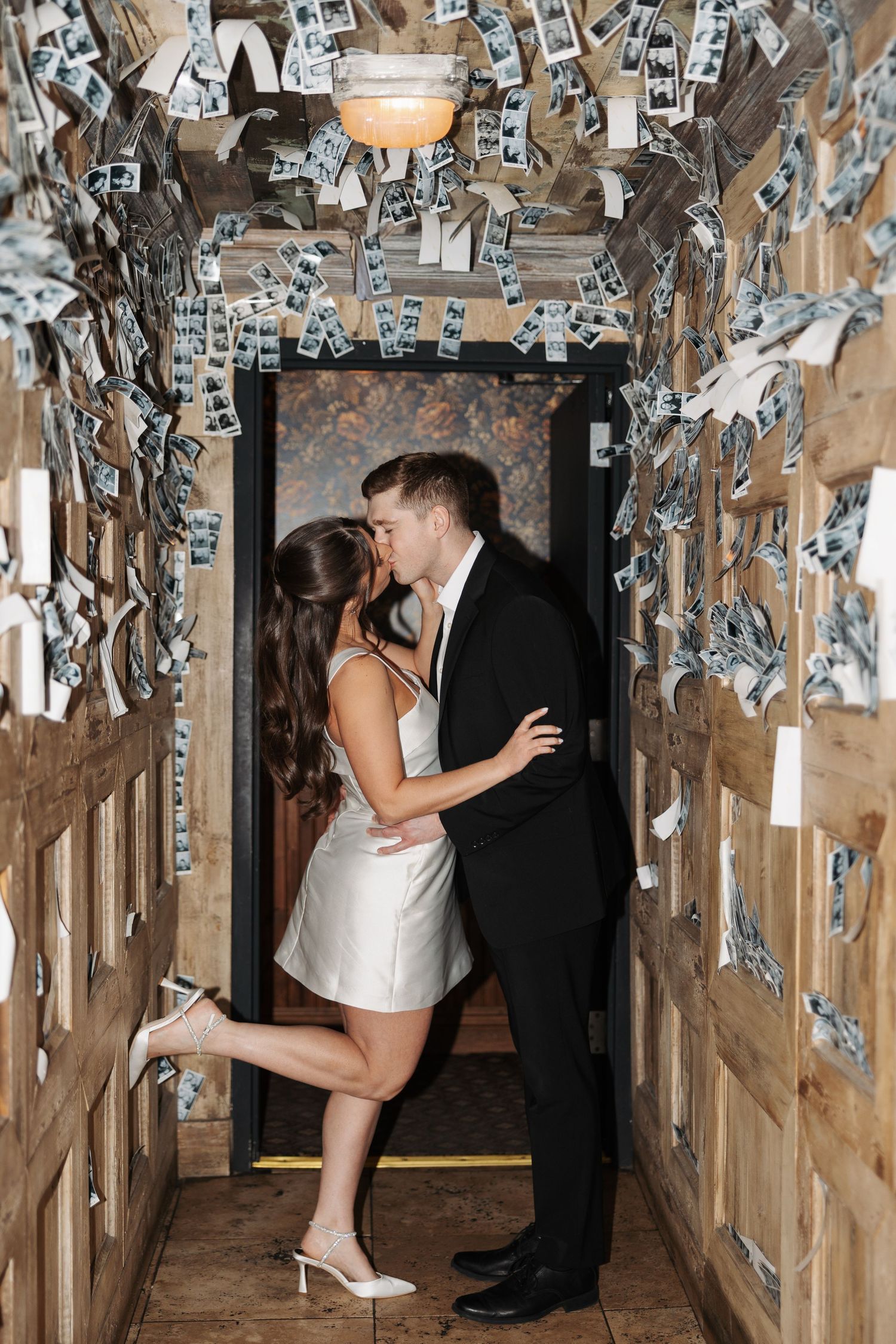 A couple shares a romantic moment in a hallway decorated with dollar bills on the walls.