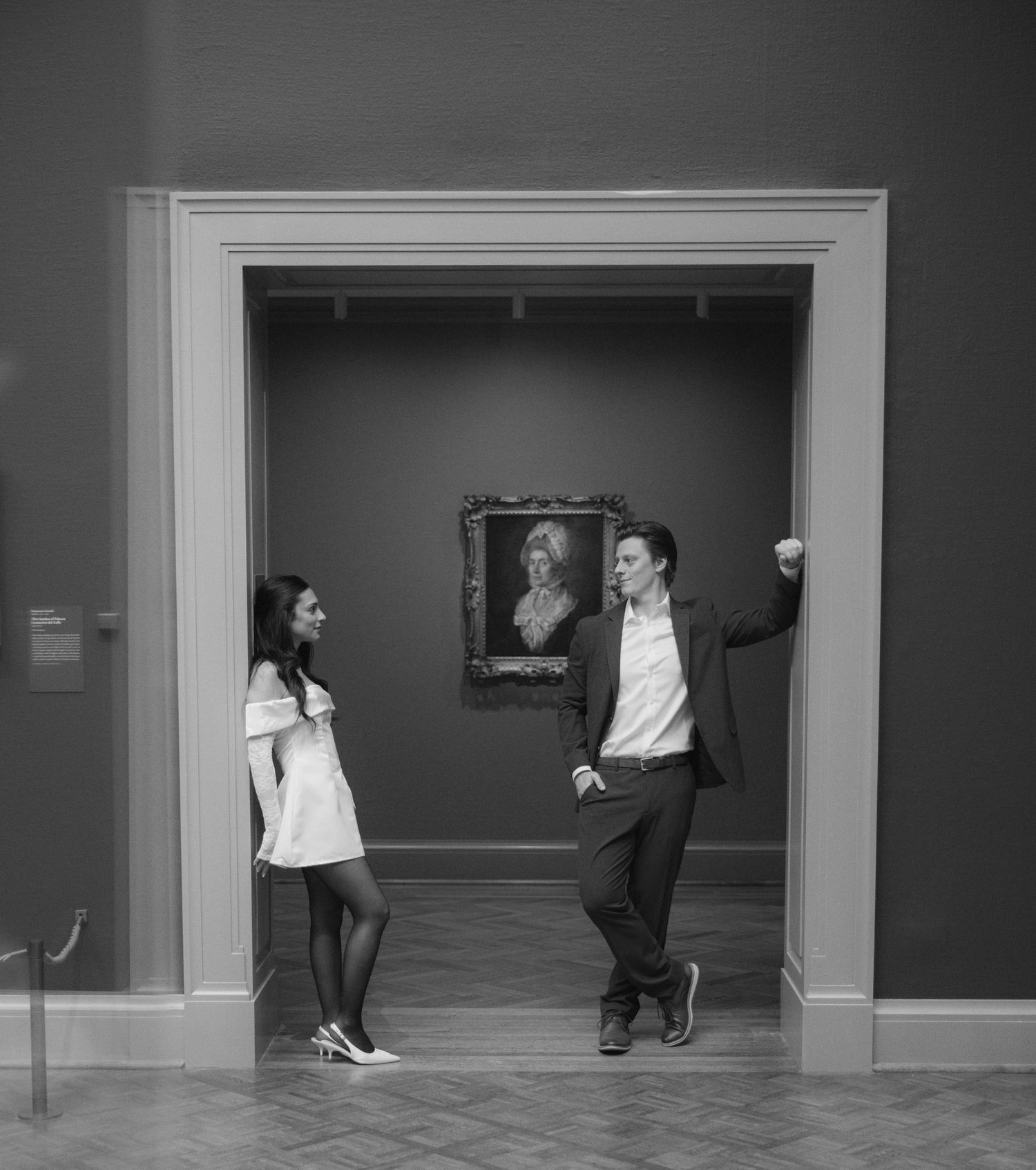 A playful black and white photo of a couple dancing in an art gallery.