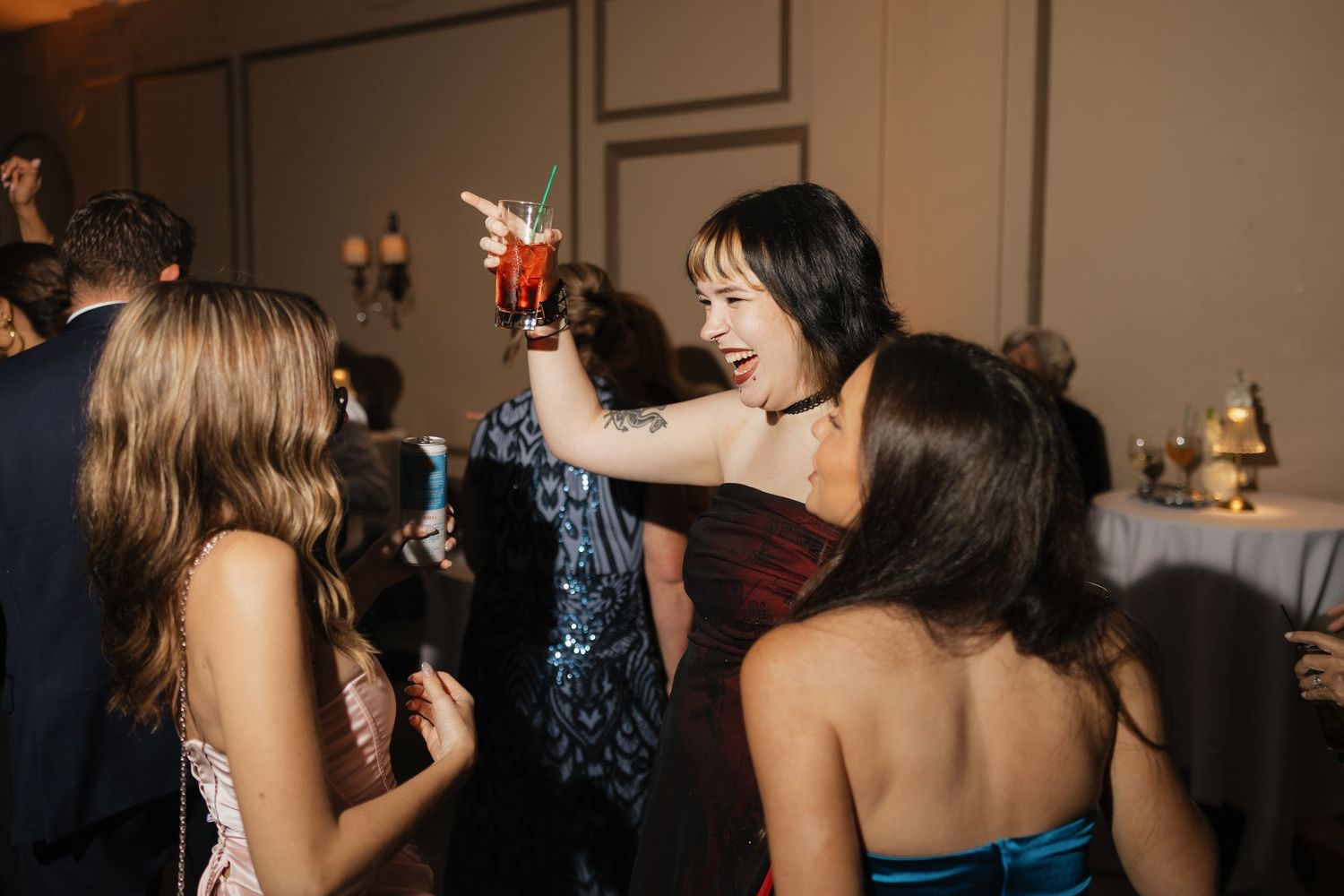 Women in formal attire toasting cocktails at an elegant evening party celebration.
