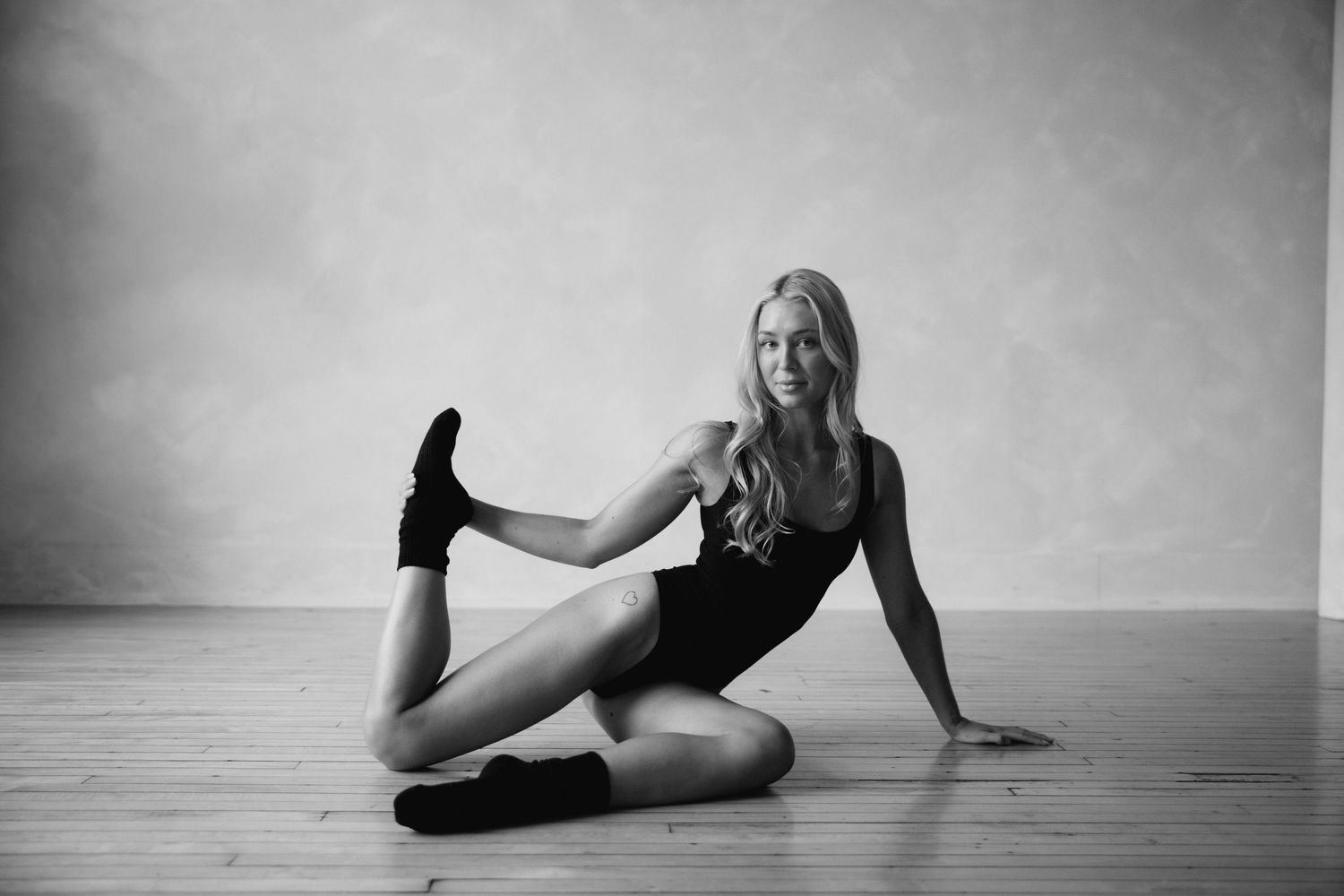 Artistic black and white photo series featuring dance-inspired poses on a wooden floor.