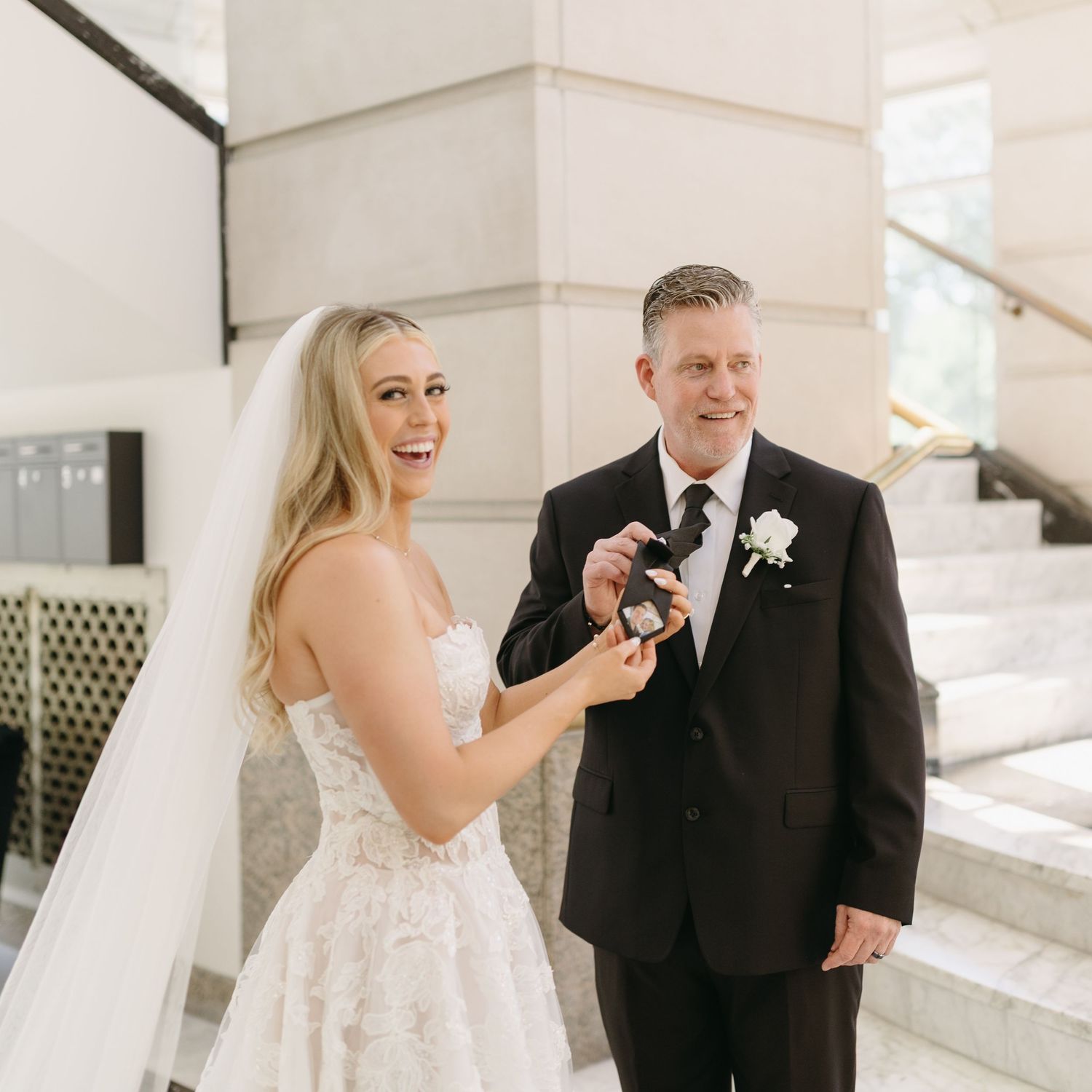A joyful first look moment between newlyweds in white dress and black suit on their wedding day.
