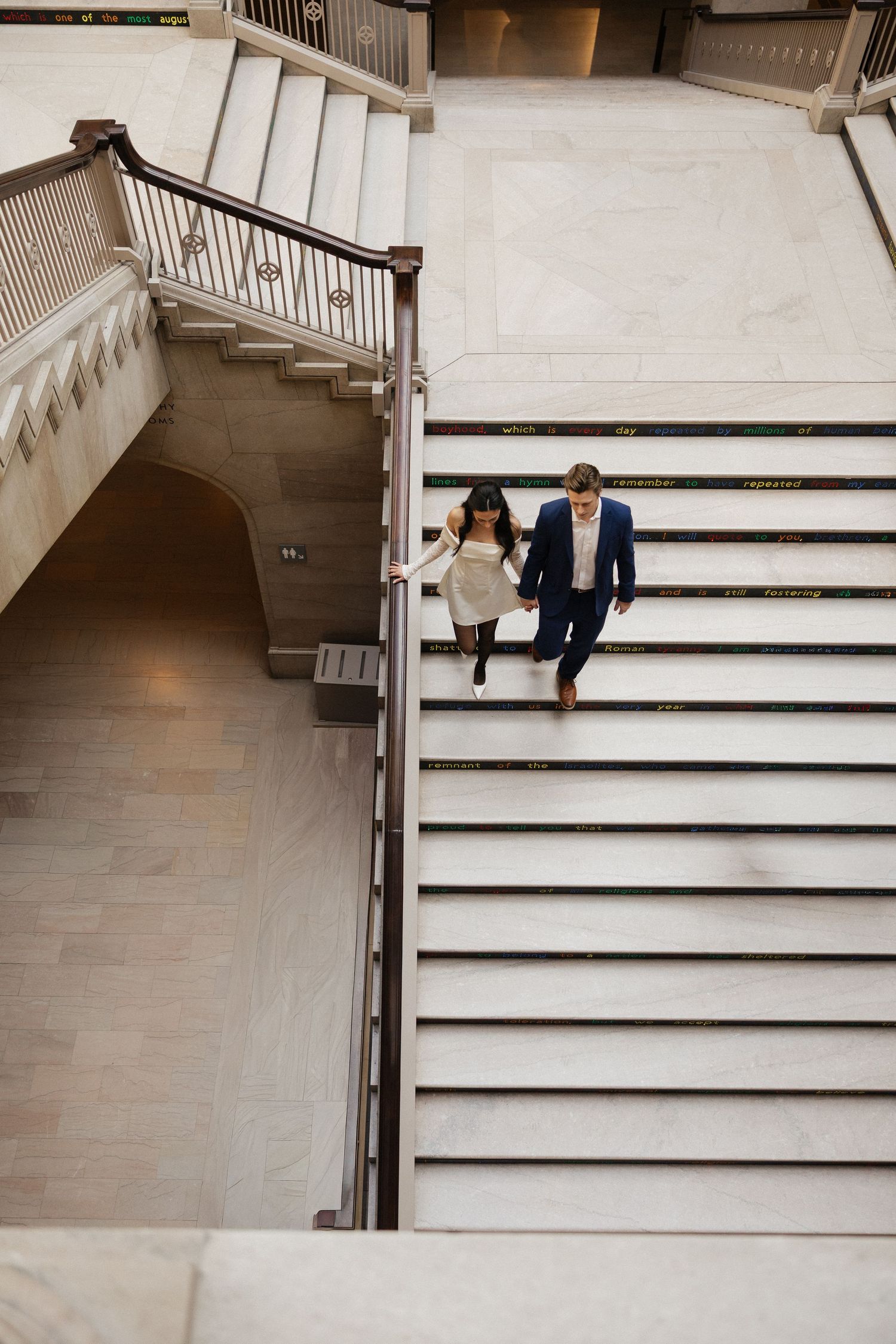 View of elegant white marble staircase with couple ascending steps.