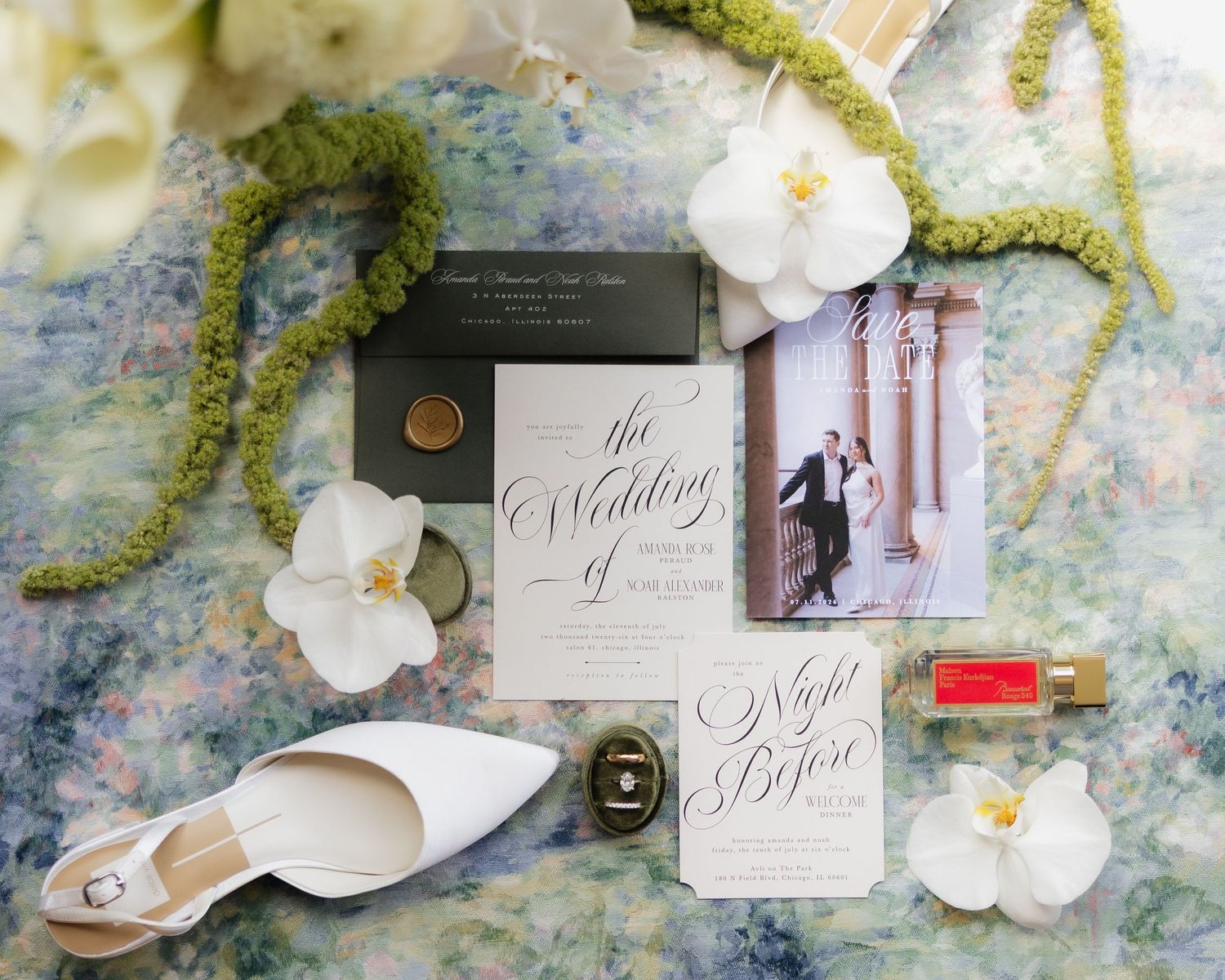 Elegant wedding invitation suite with calligraphy, white heels, orchids, wax seal, and save the date card on floral backdrop.