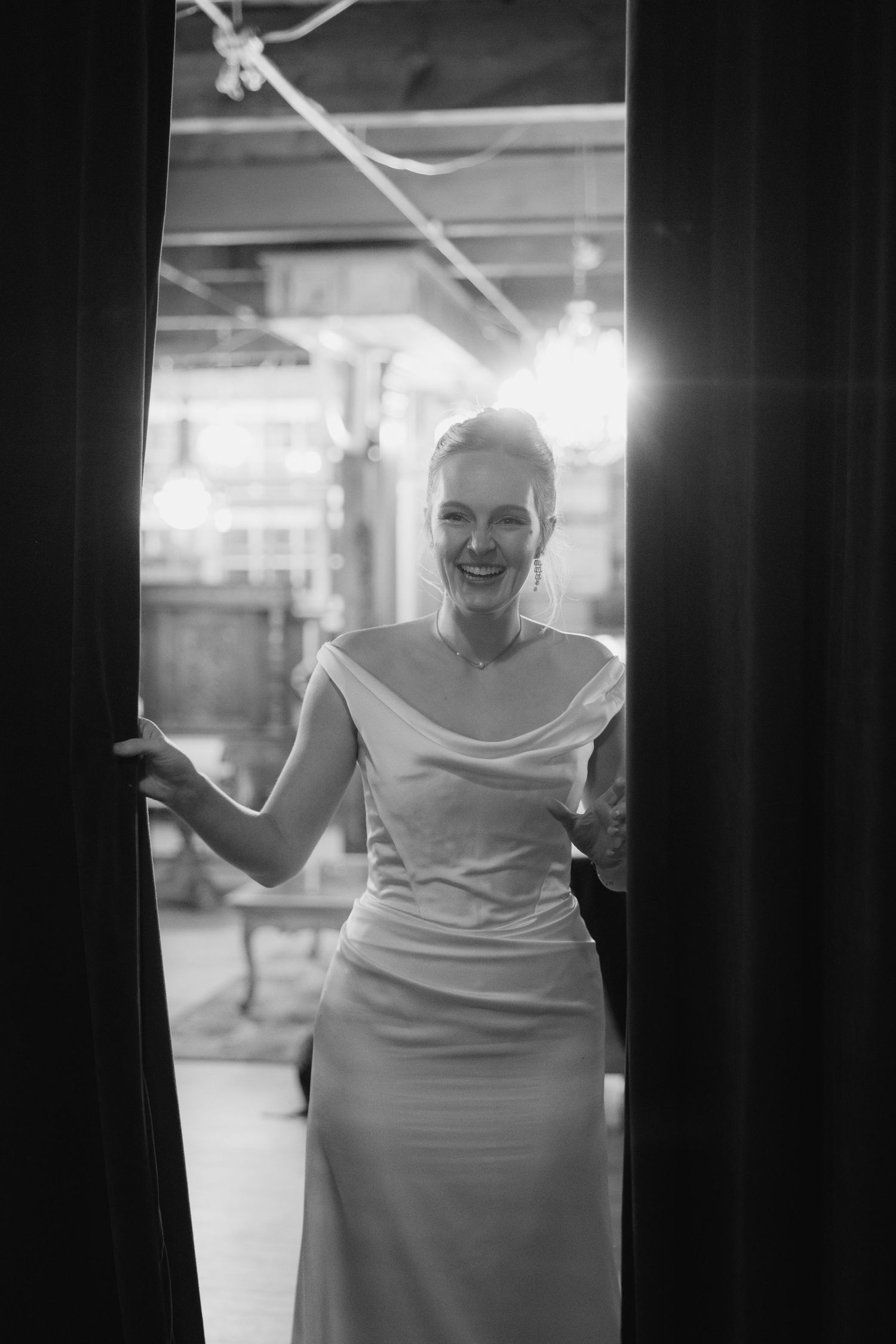 A sequence of black and white photos showing someone in a white dress posing playfully between dark pillars.