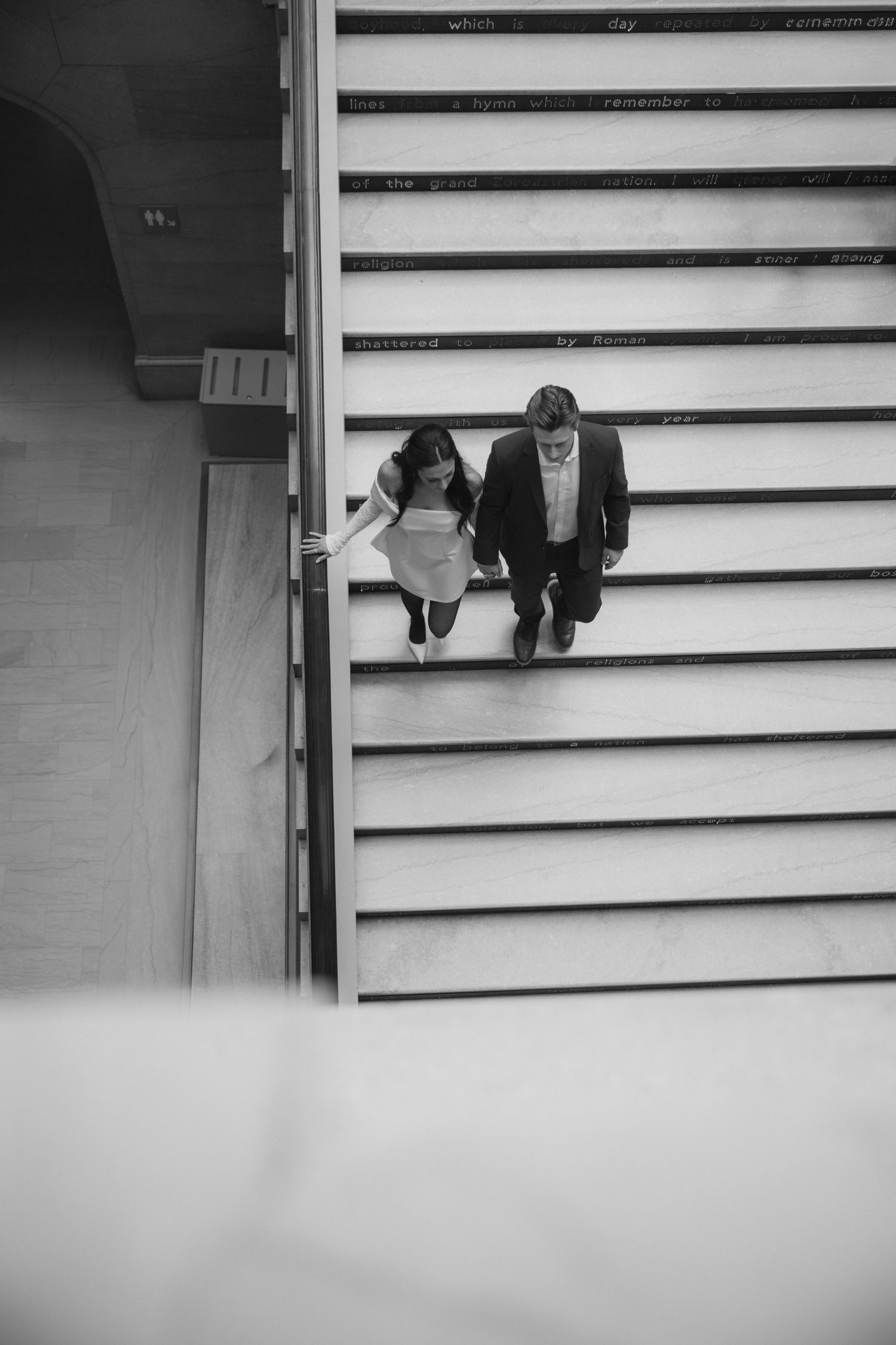 Black and white view of figures descending concrete stadium-style steps.