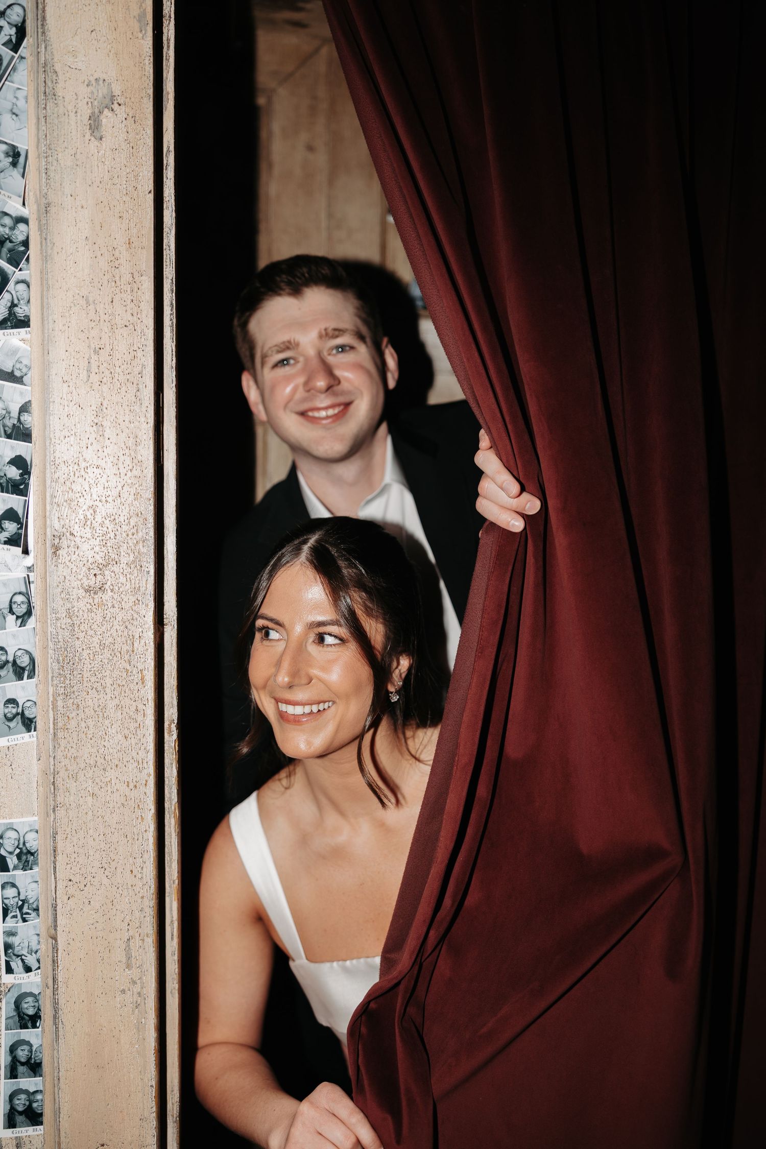 Three photo booth style images show people playfully posing with a burgundy curtain in a vintage setting.