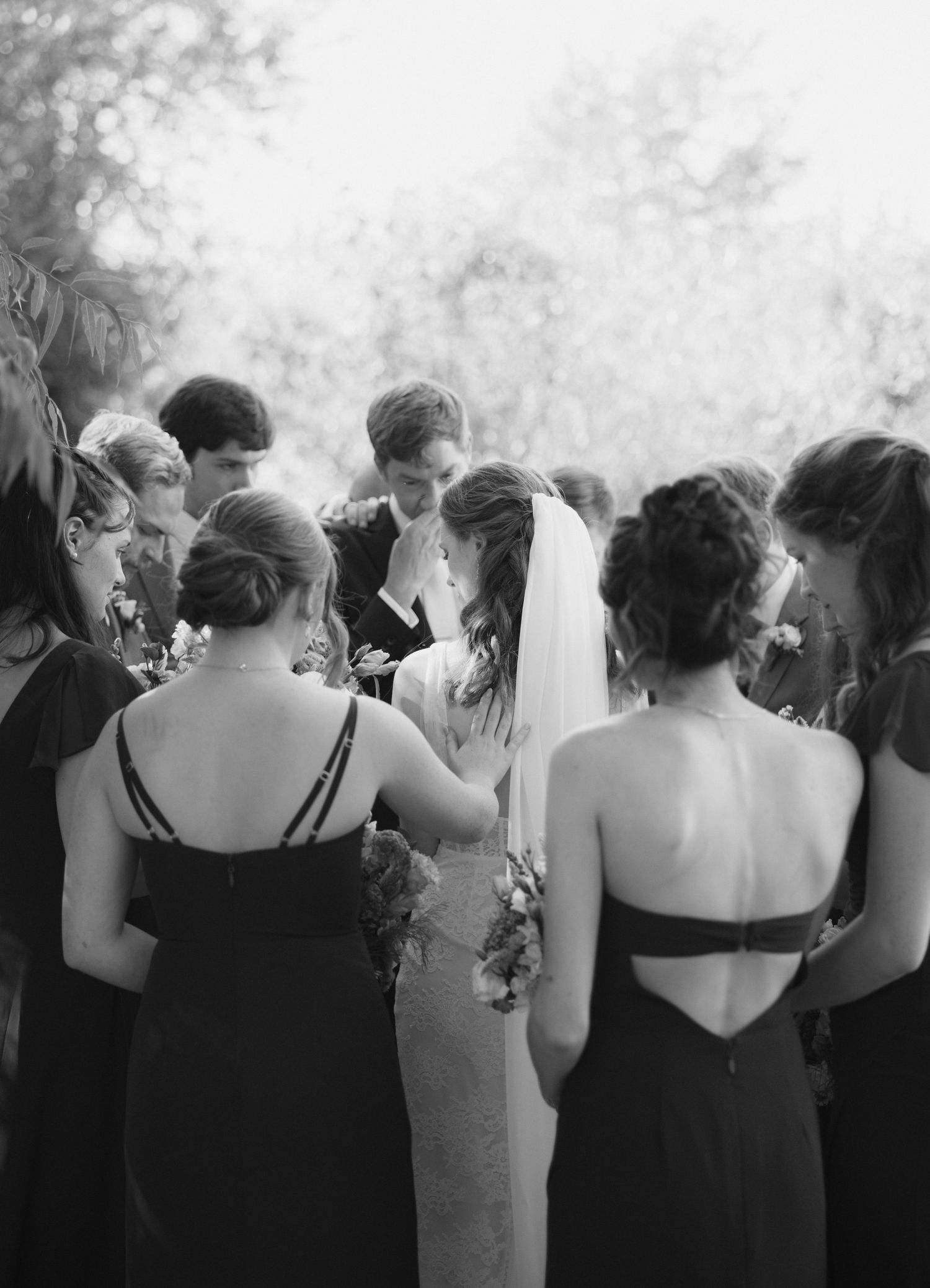 Black and white photo of bridesmaids in dark dresses standing in a row.