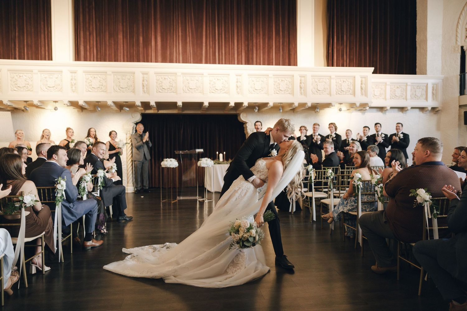 A panoramic view of a wedding ceremony in a modern venue with wooden panels and elegant white decor.