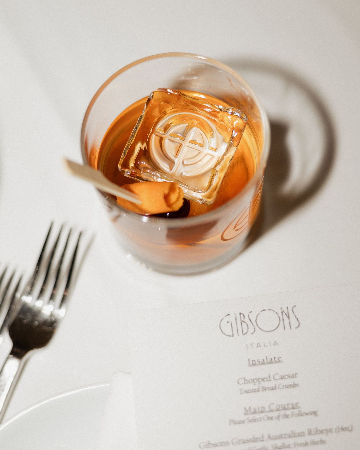 Elegant restaurant menu cards and wine glasses arranged in a minimalist style against a light background.