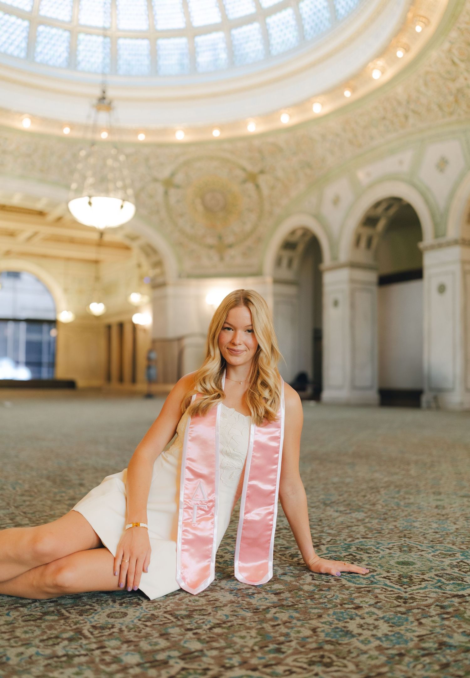 A series of photos showing someone lying on an ornate carpet under a grand domed ceiling with classical architecture.