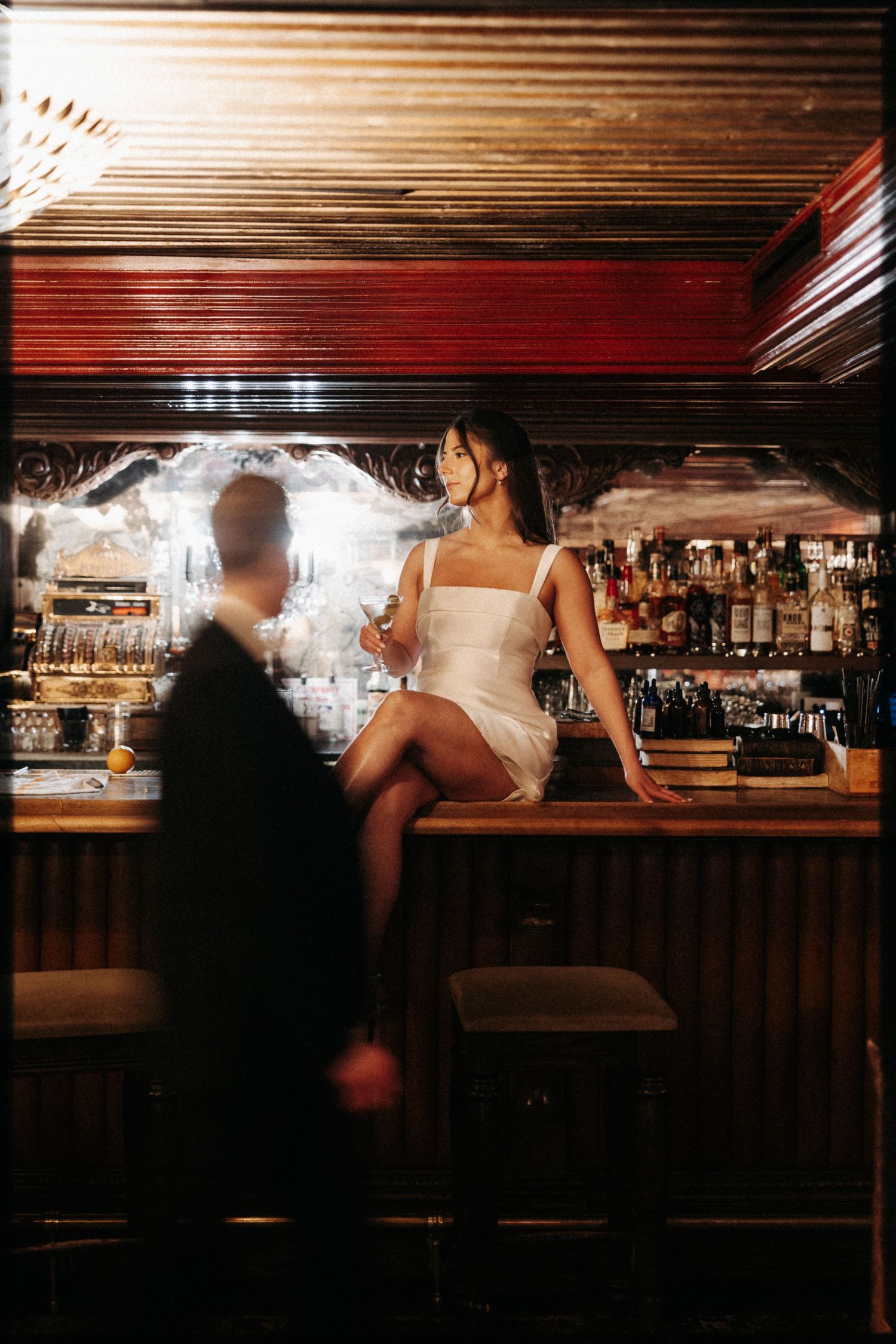 A sequence of blurred motion shots showing people at a dimly lit bar counter with warm lighting and wood paneling.