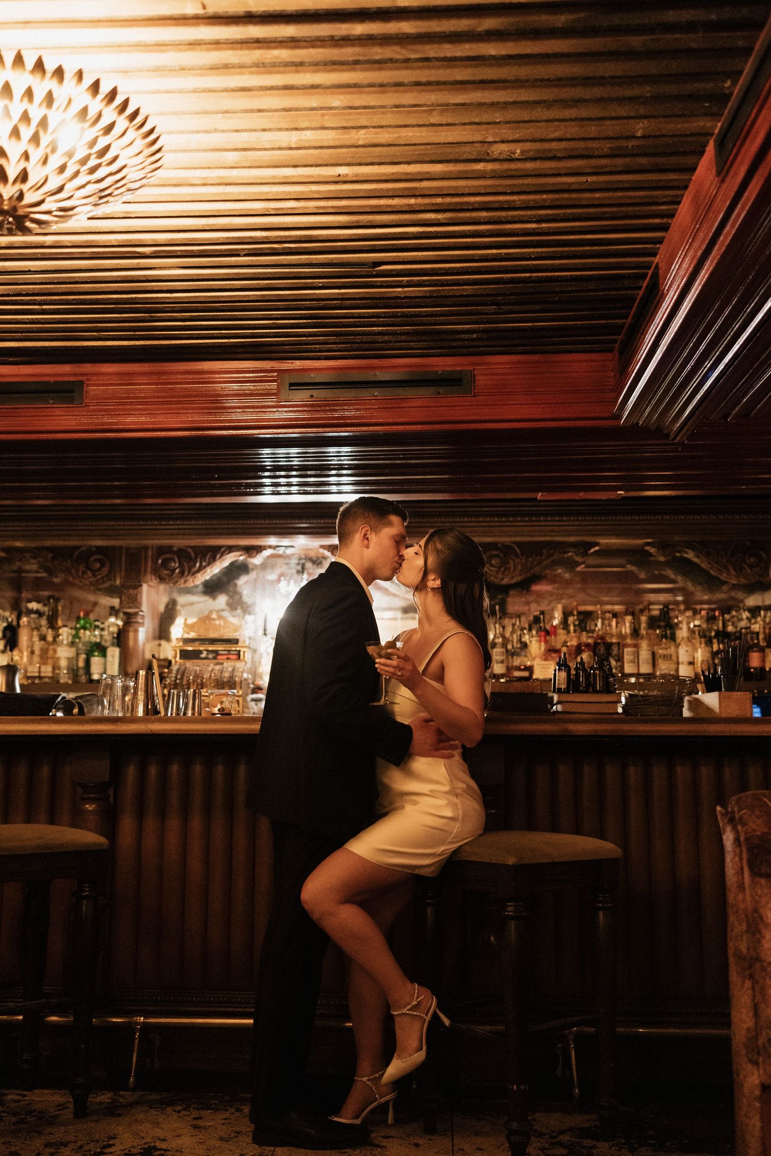 A sequence of romantic silhouettes dancing and embracing in a dimly lit bar setting with wooden ceiling beams.