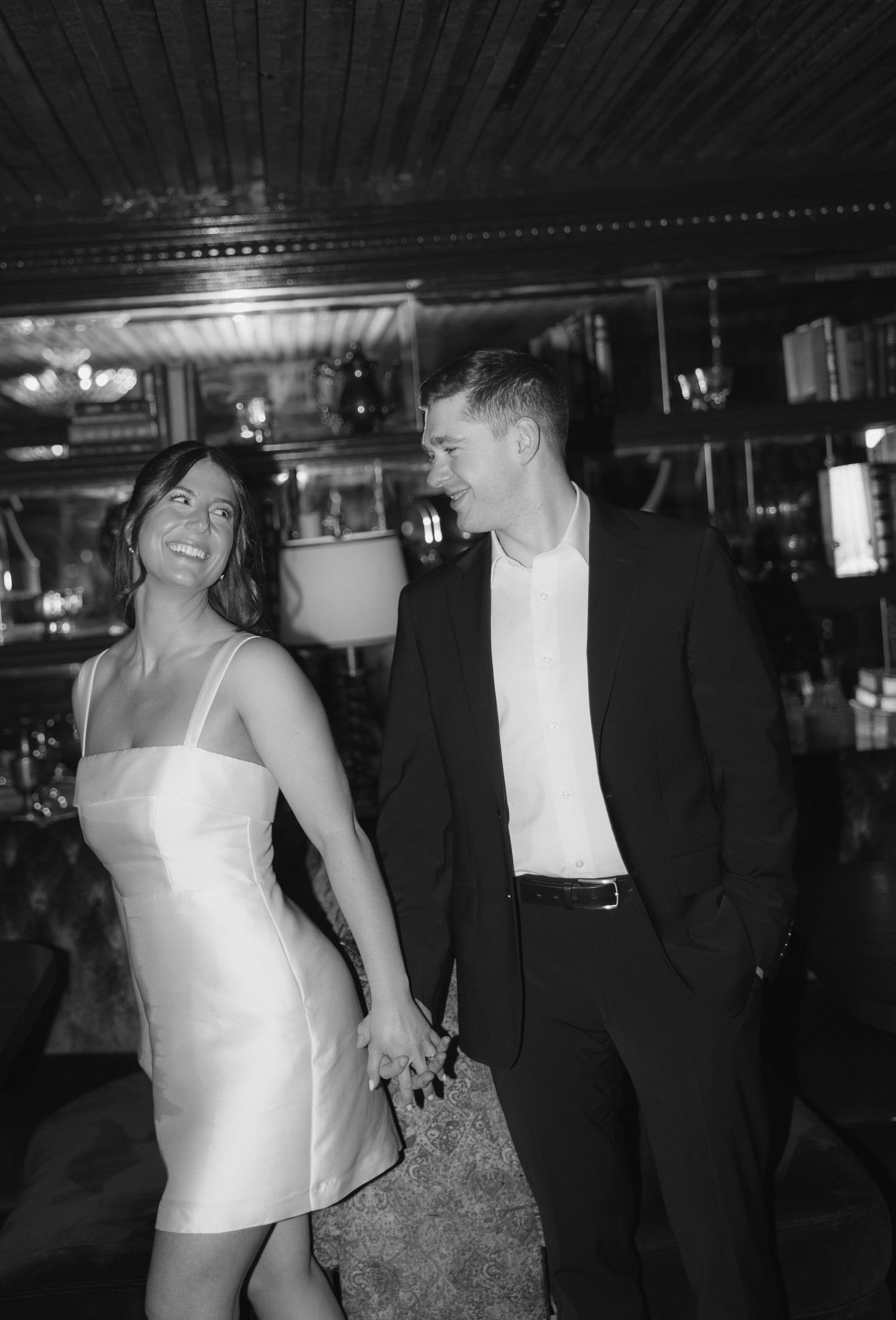 Couple dancing and laughing together at a dimly lit party venue with joyful expressions.