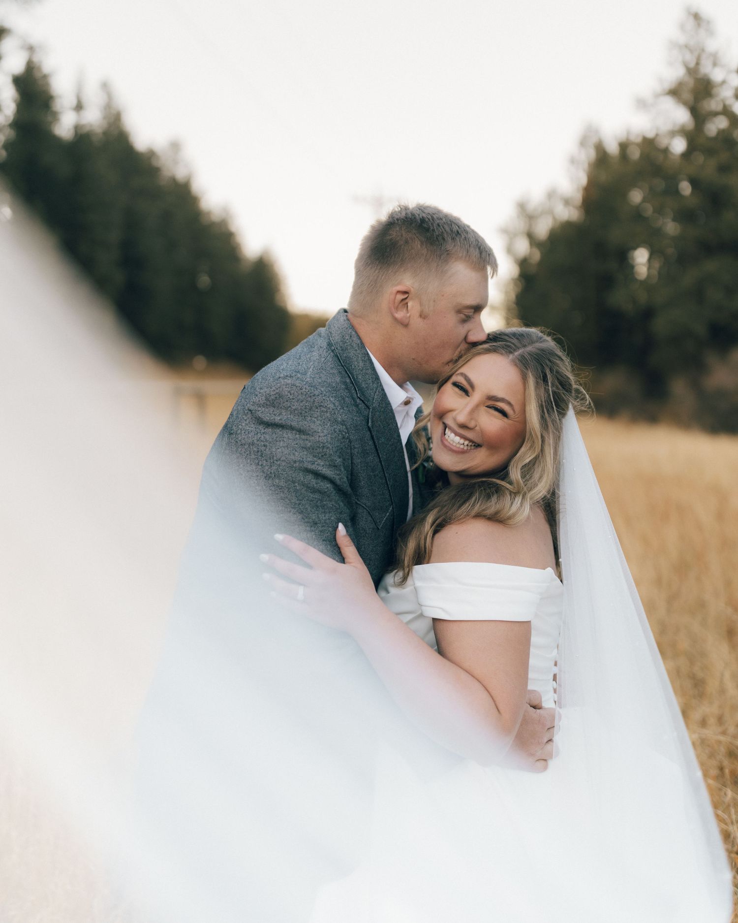 Romantic wedding portraits captured in a golden field at sunset.