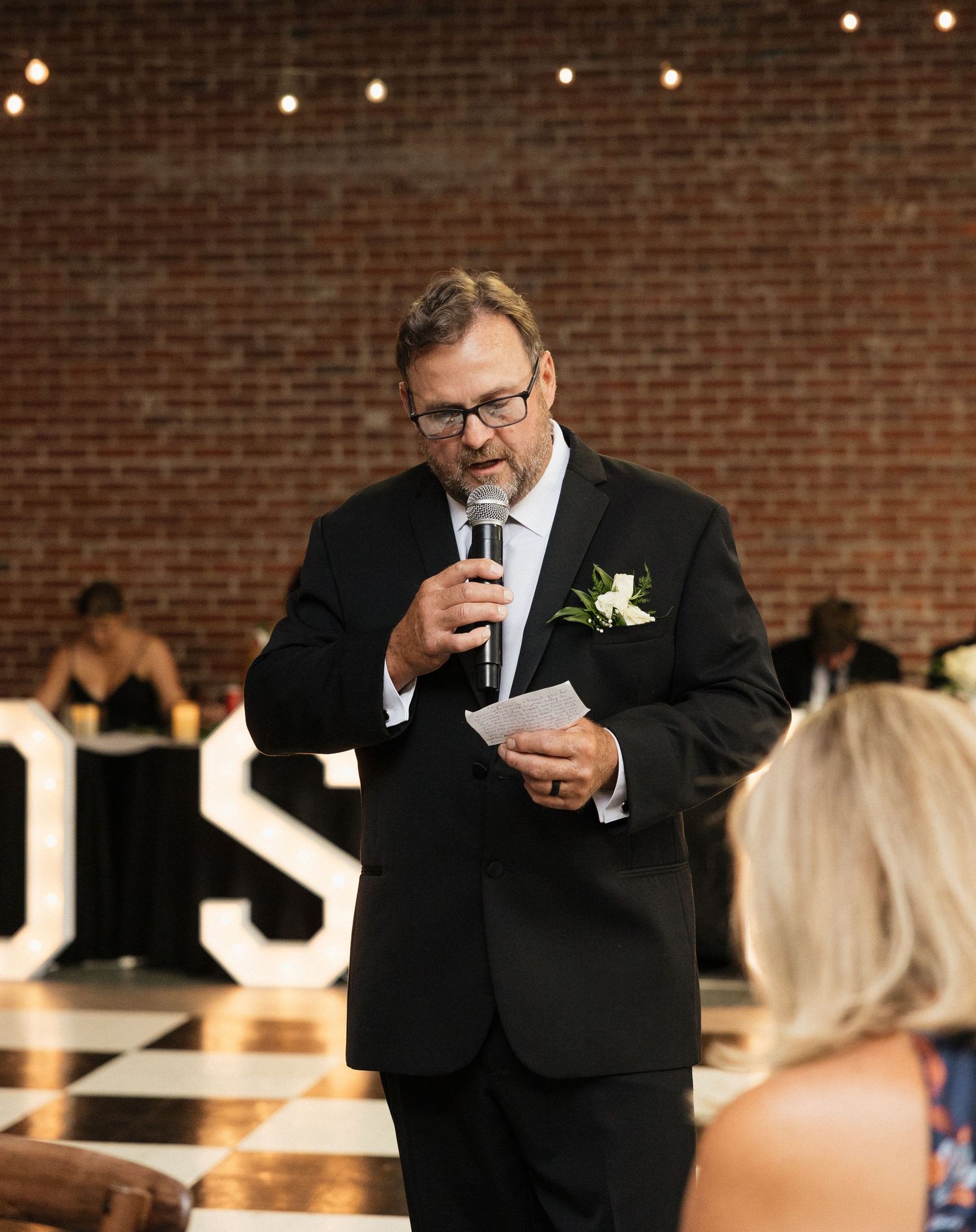 Wedding reception venue with exposed brick walls and string lights creating ambient atmosphere.