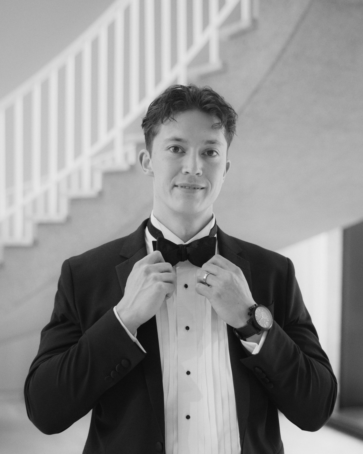 Black and white sequence showing someone adjusting a bow tie while wearing formal attire.